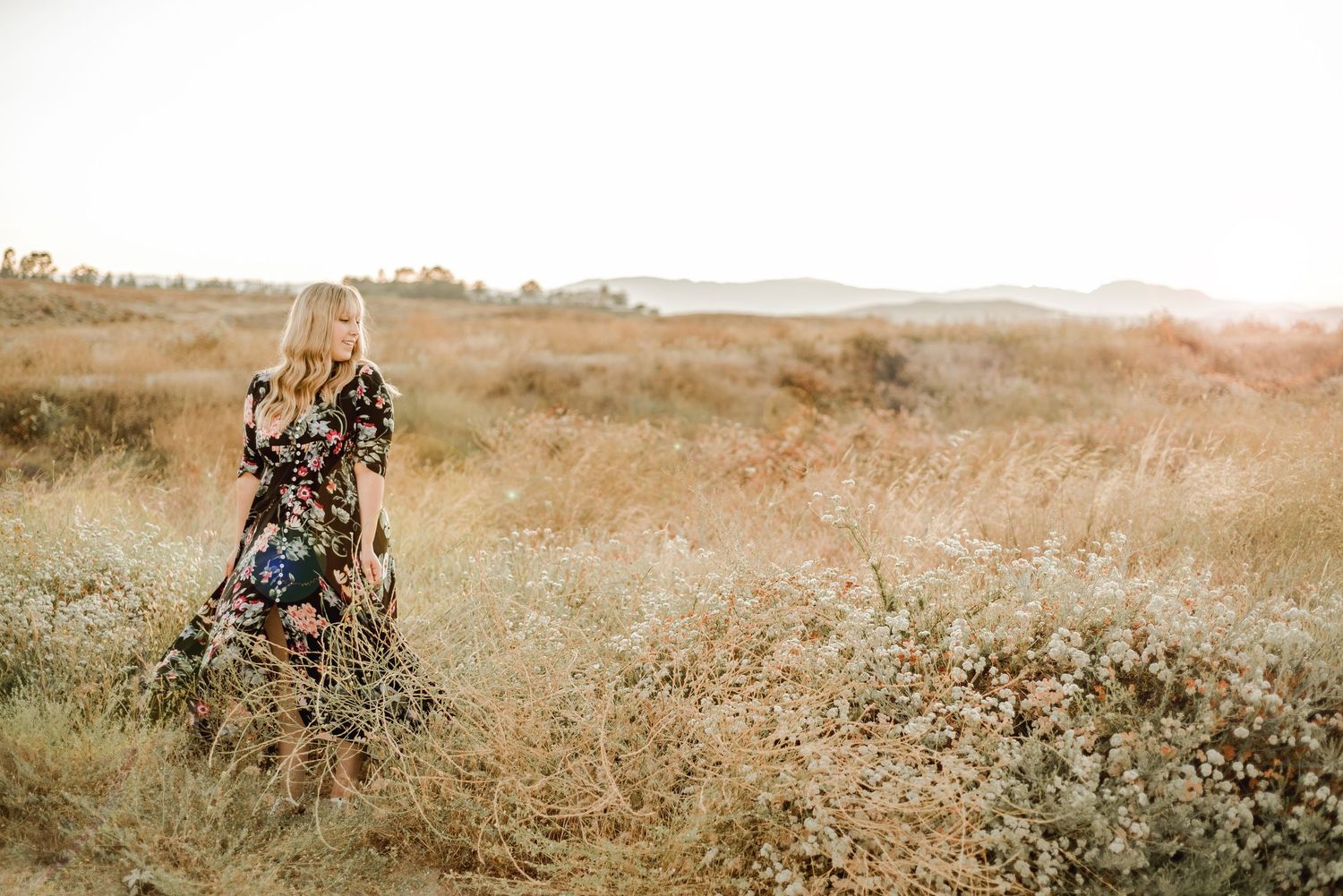 A floral dress catches the breeze in a golden field during sunset.