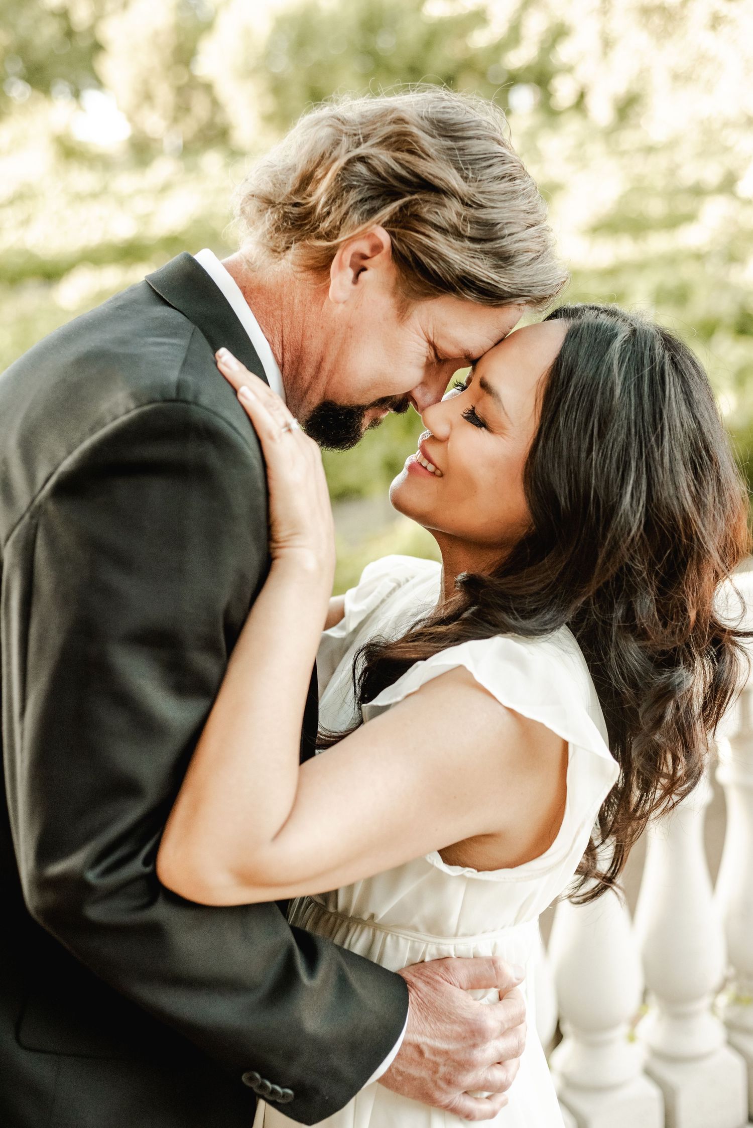 A romantic embrace captured in soft natural lighting during an outdoor photoshoot.