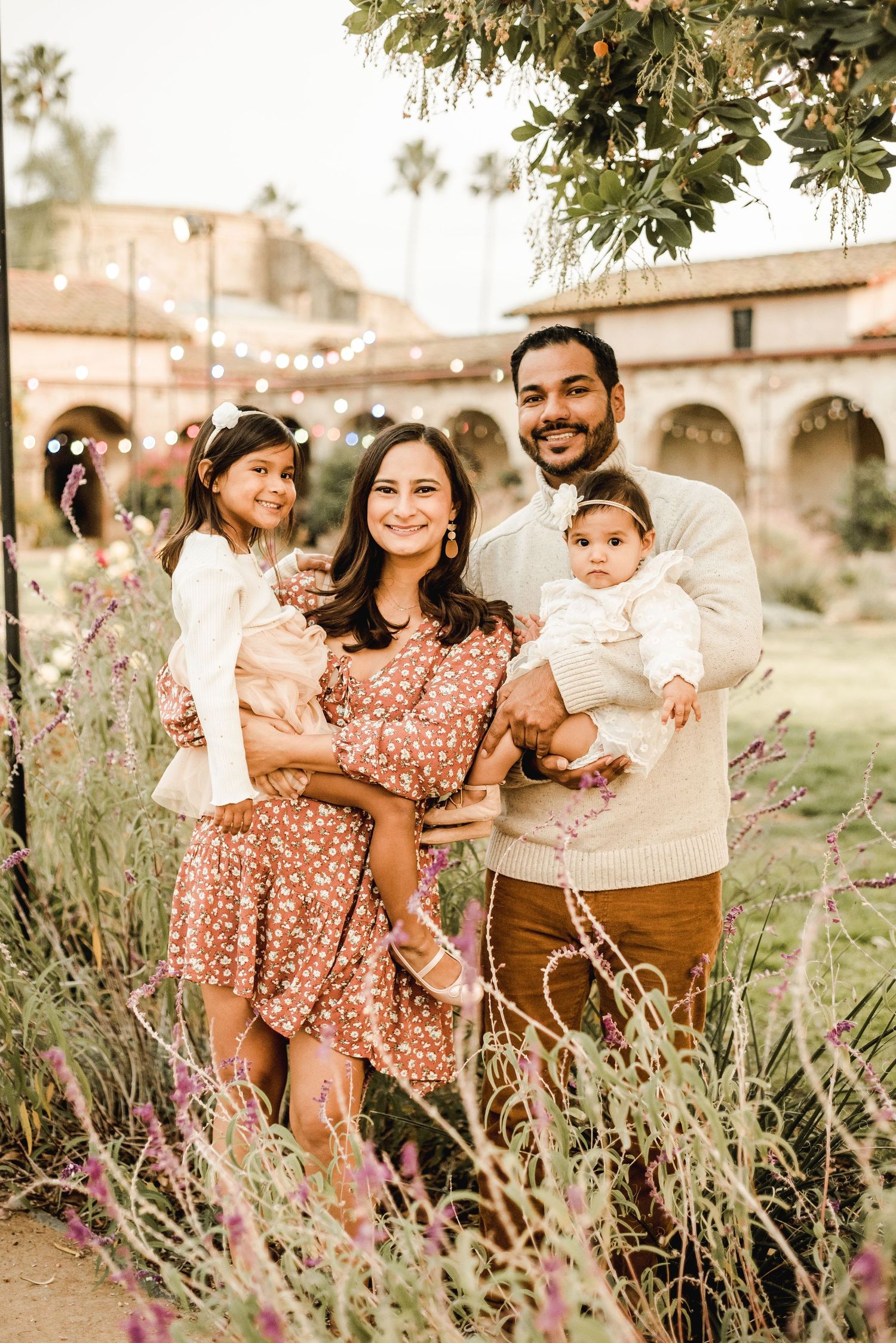 A family portrait session in a garden with lavender plants and warm sunset lighting.