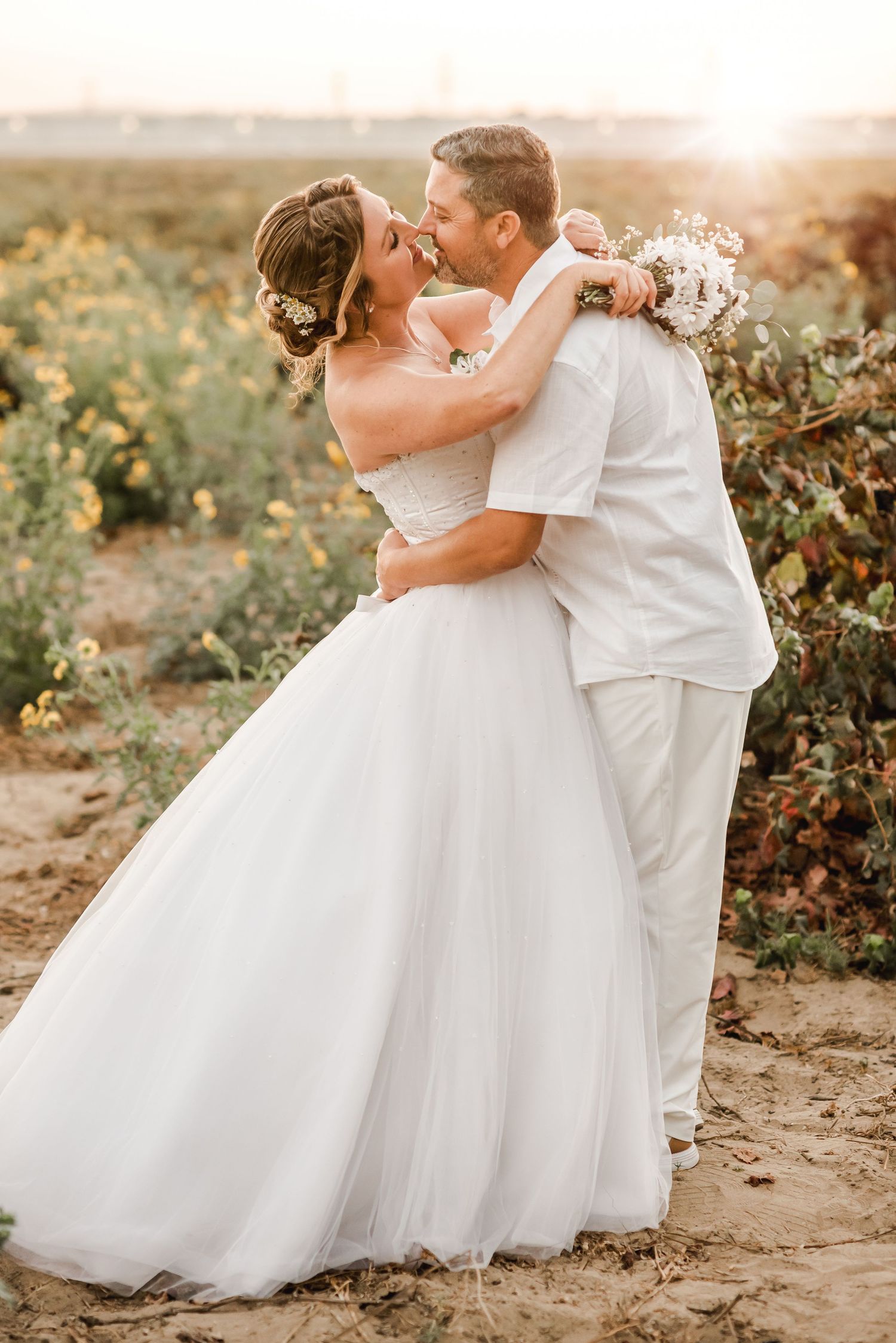 A joyful wedding embrace photographed in a vineyard during sunset.