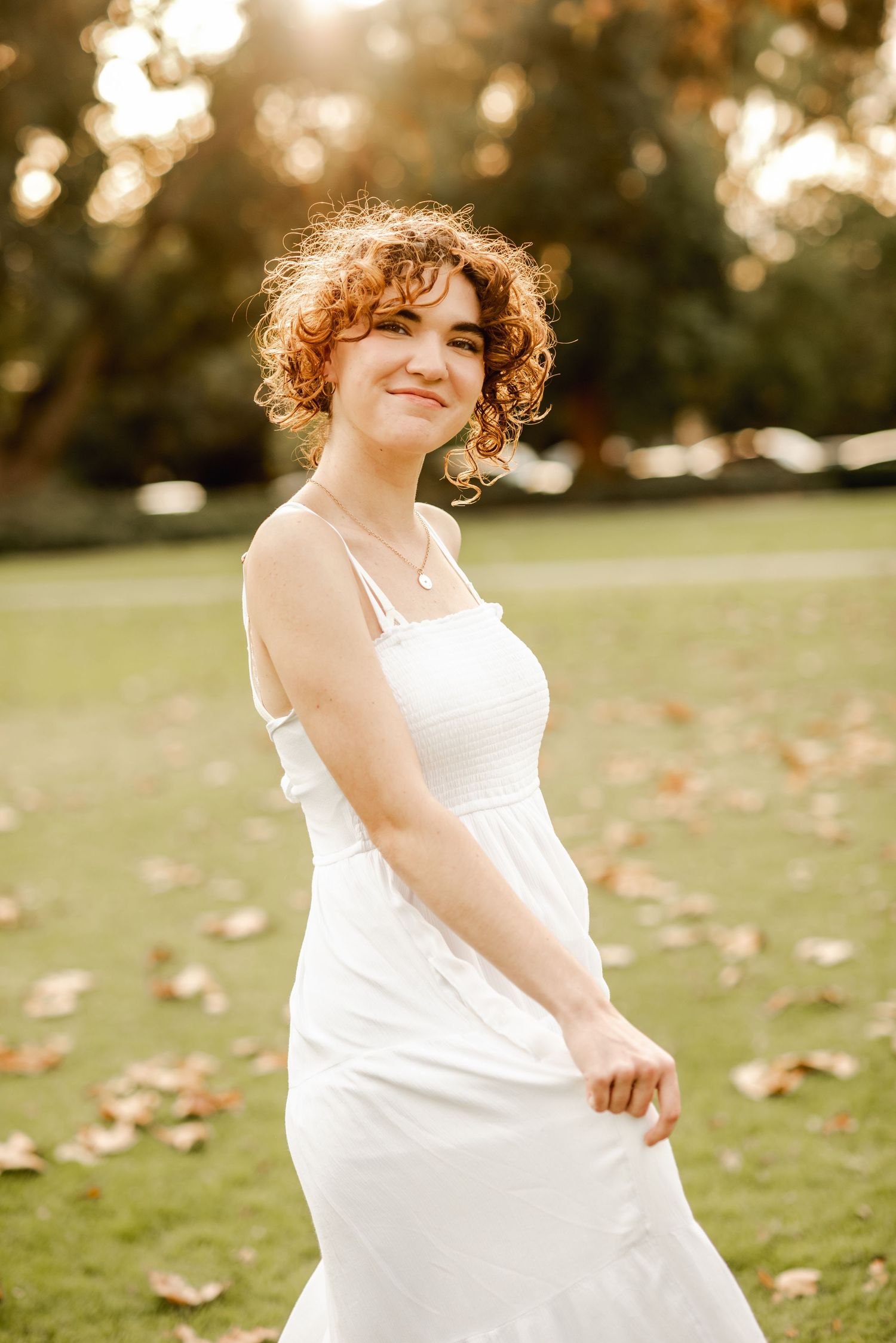 Joyful portrait session in a white dress spinning on grass during golden hour.
