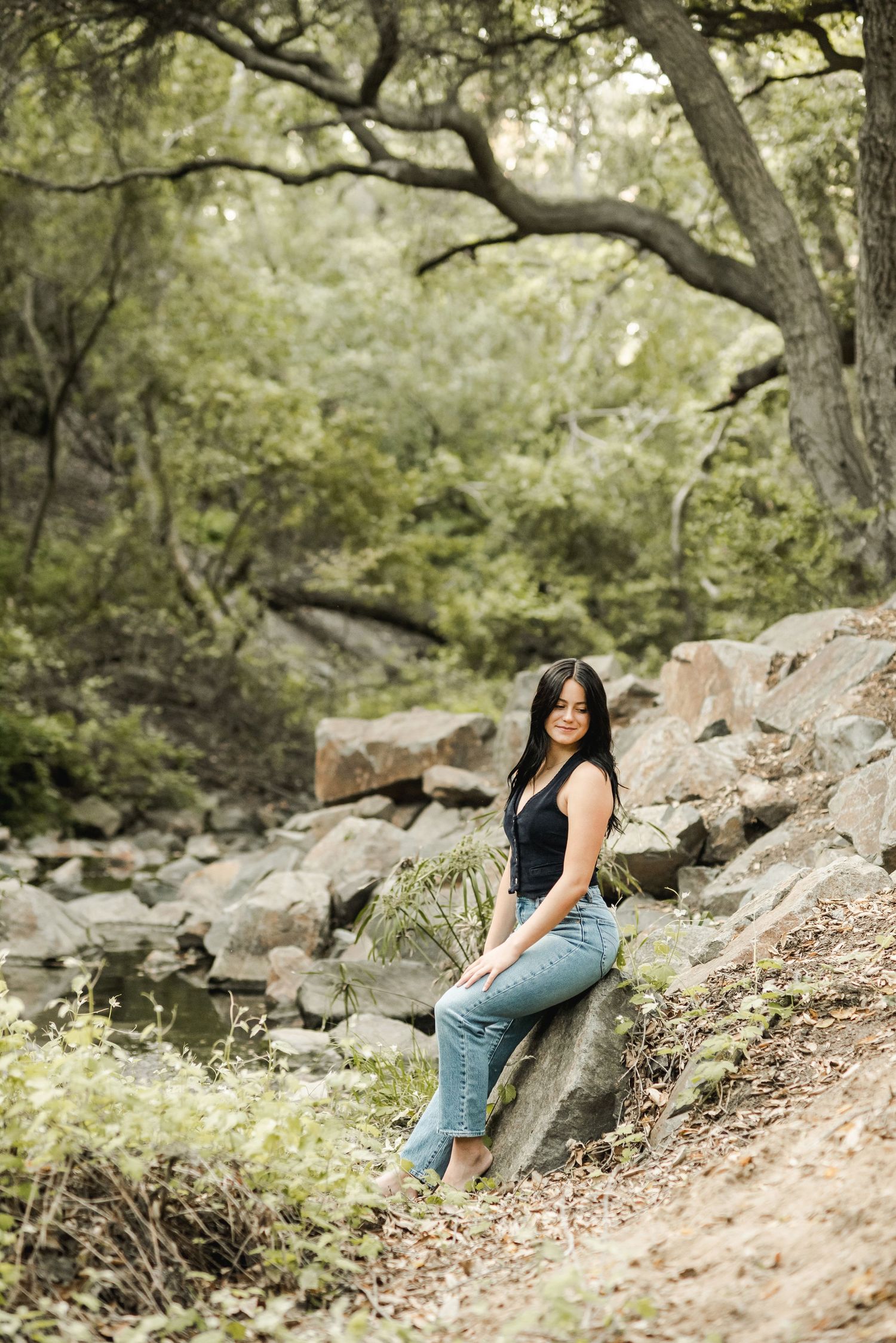 Casual outdoor portrait session on rocky terrain surrounded by lush greenery.