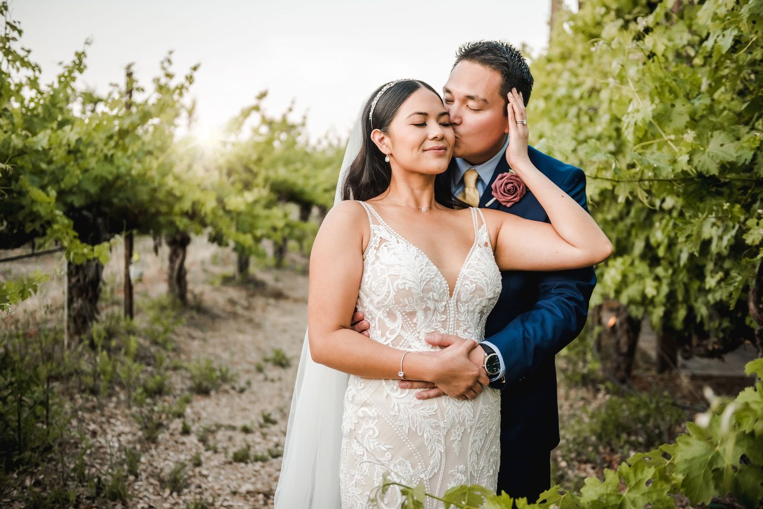 An intimate moment between newlyweds among the vineyard rows at sunset.