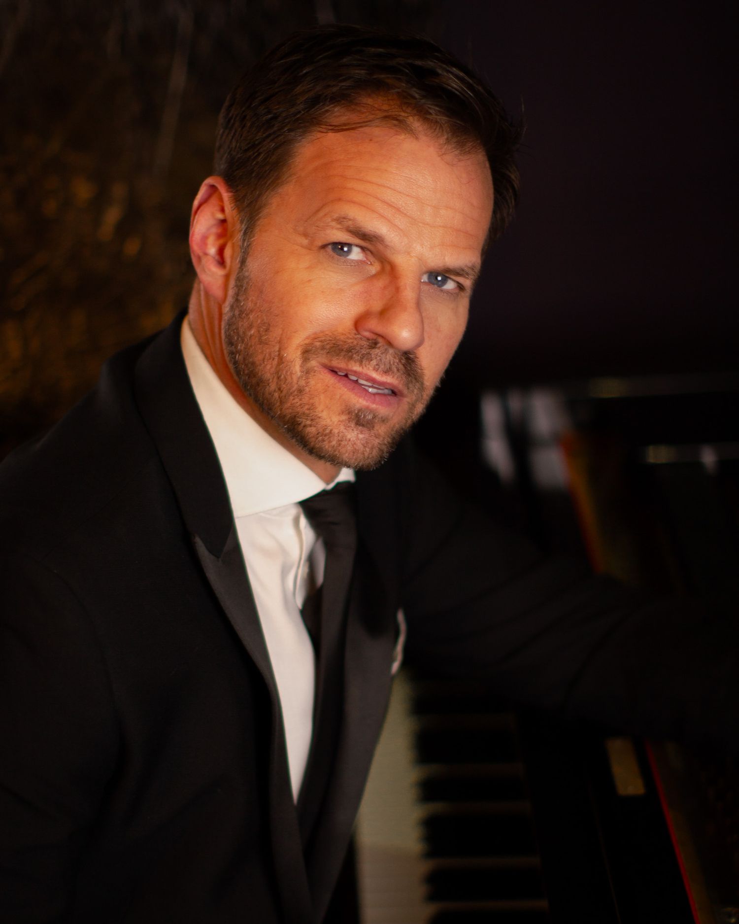 Colour image of one of our clients leaning against a piano, part of our 'Swing into Spring' series for Ben Richards.