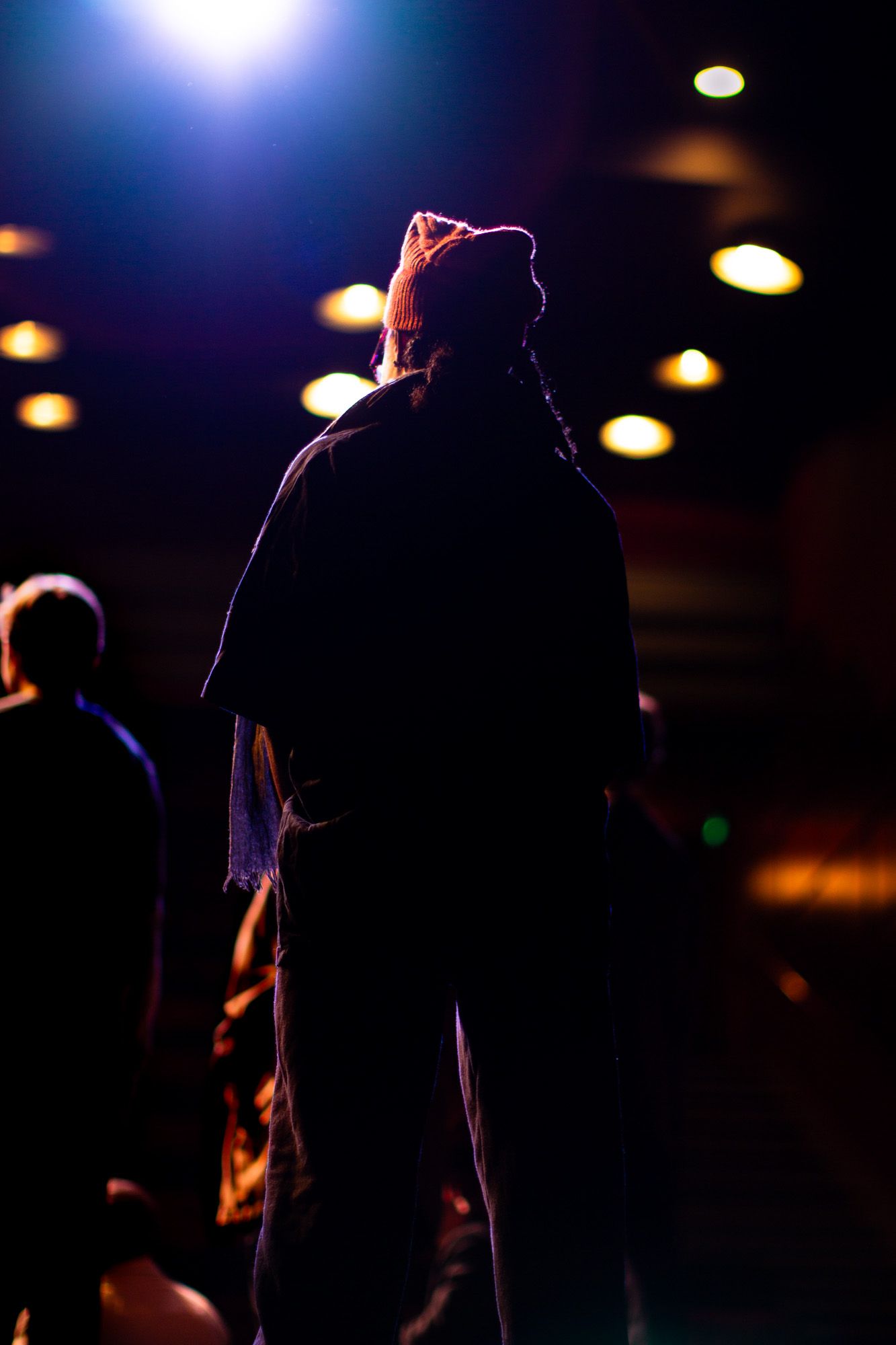 Colour production image. Showing a figure on stage looking out into the bright lights of an auditorium
