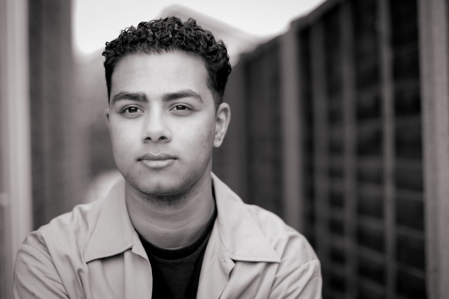 B&W portrait image of a client from for a headshot session. Smiles with a nice soft background, focusing just on the clients features