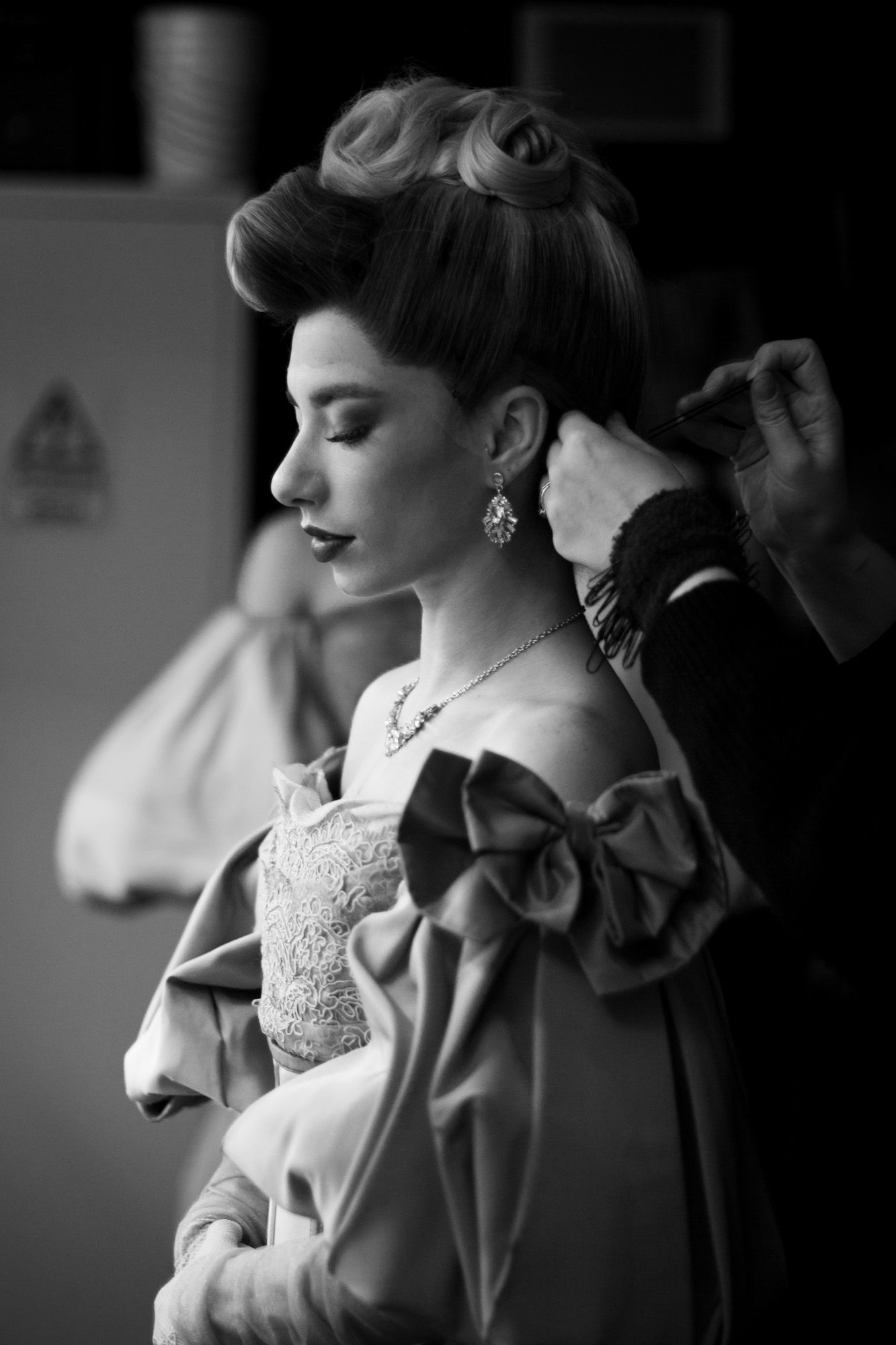 Black and white image of one of a performer at Moulin Rouge! The Musical in London. Backstage image of a performer during a wig change.