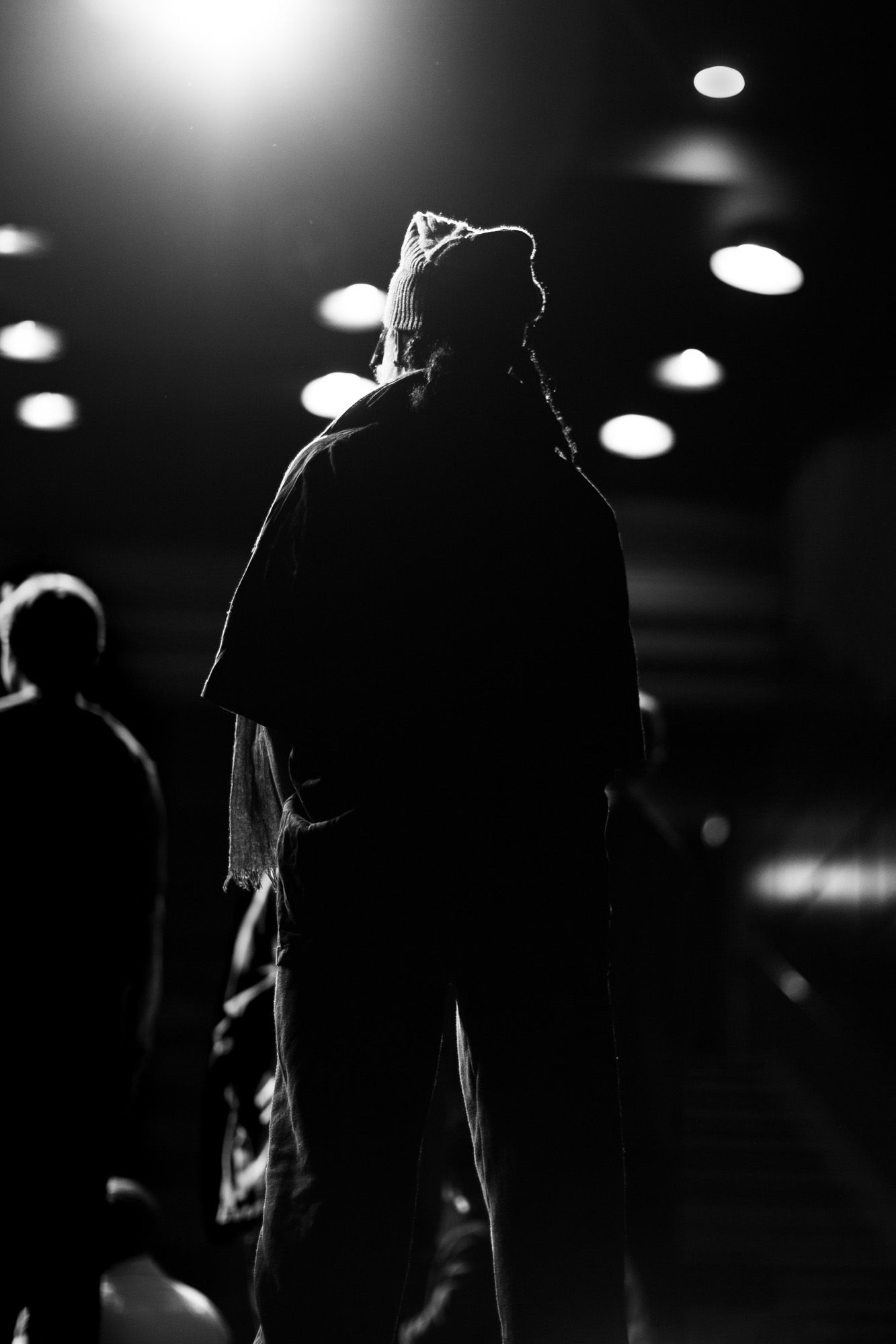 Black and white production image for a client. Showing a figure on stage in front of bright stage lights.