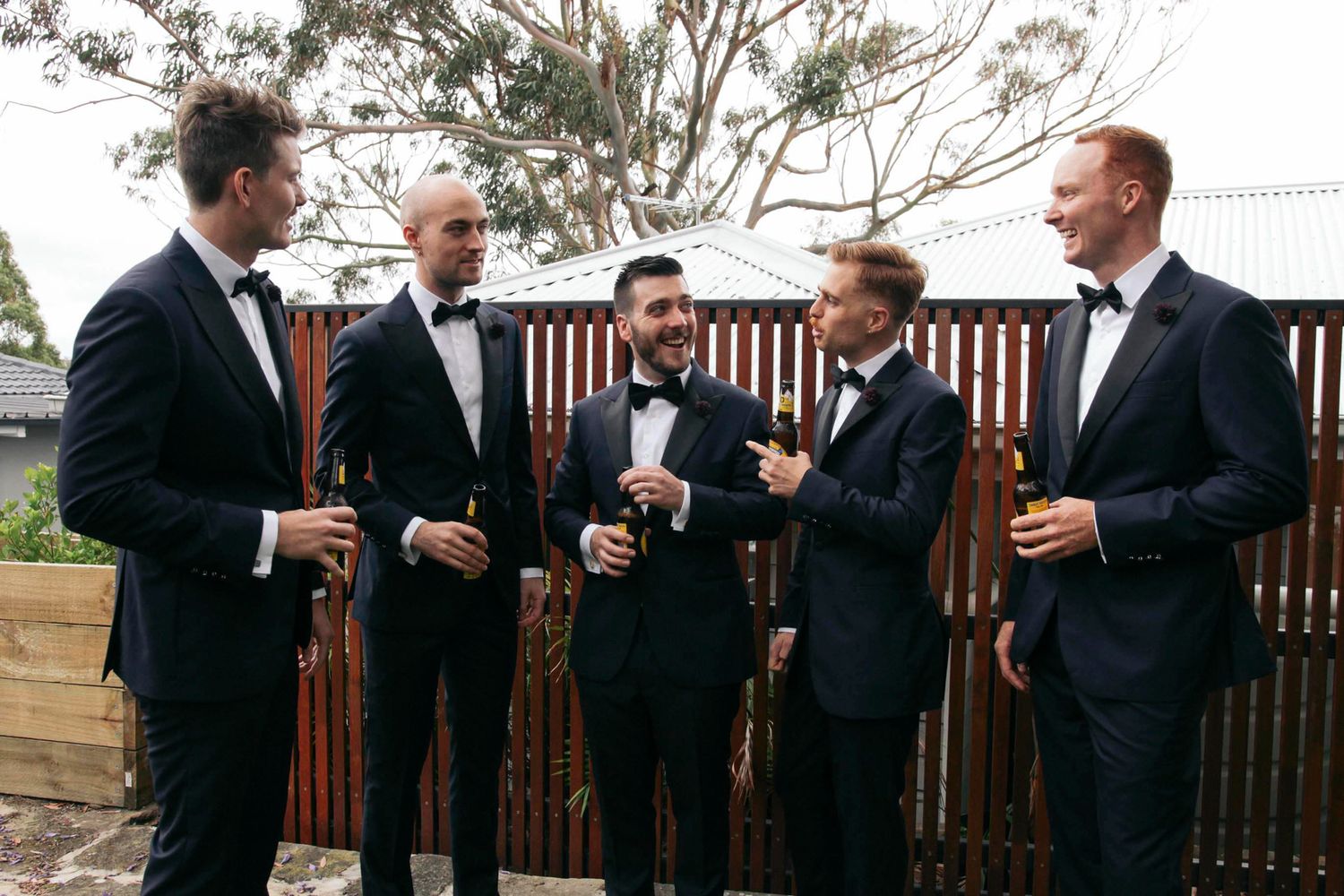 Black-tie groom and groomsmen portrait showing fine tailoring by The Suit Shop and Rembrandt details.