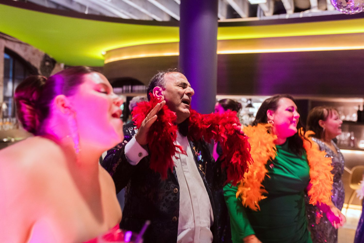 Guests dressed in extravagant Met Gala theme attire celebrating on the dance floor.