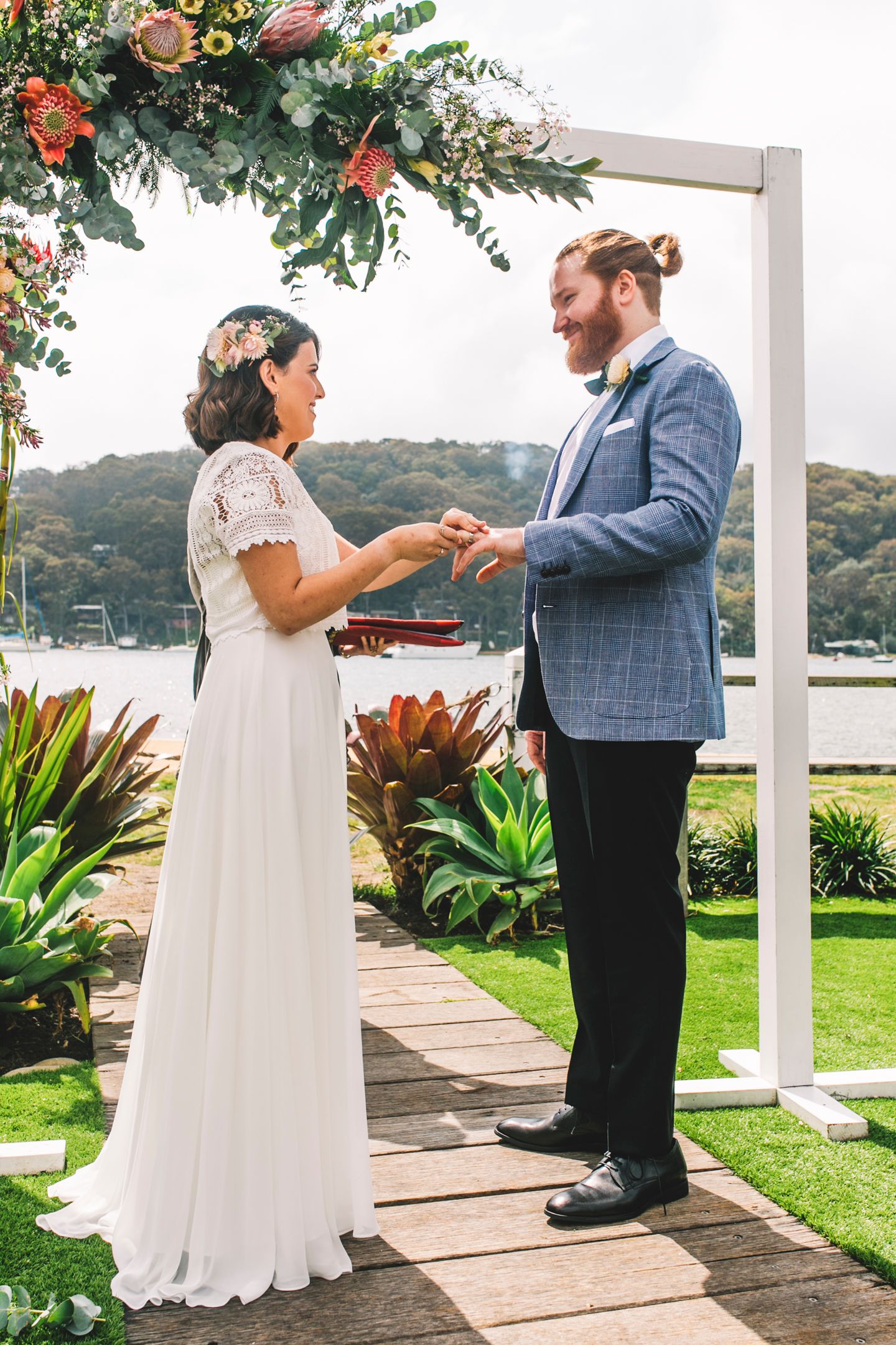 Close up of Matthew Ely engagement and wedding rings exchange against a coastal background.