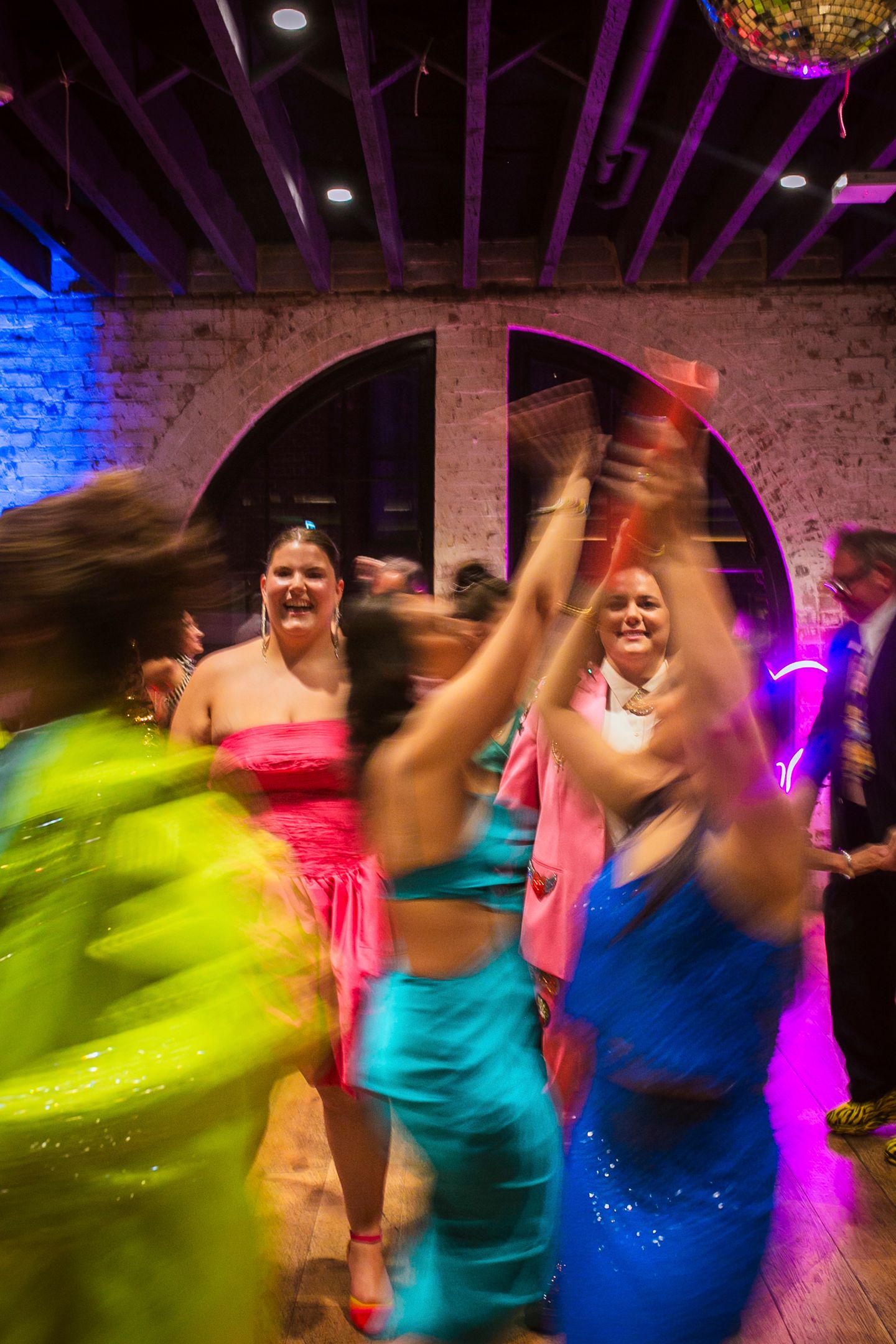 Guests dressed in extravagant Met Gala theme attire celebrating on the dance floor.