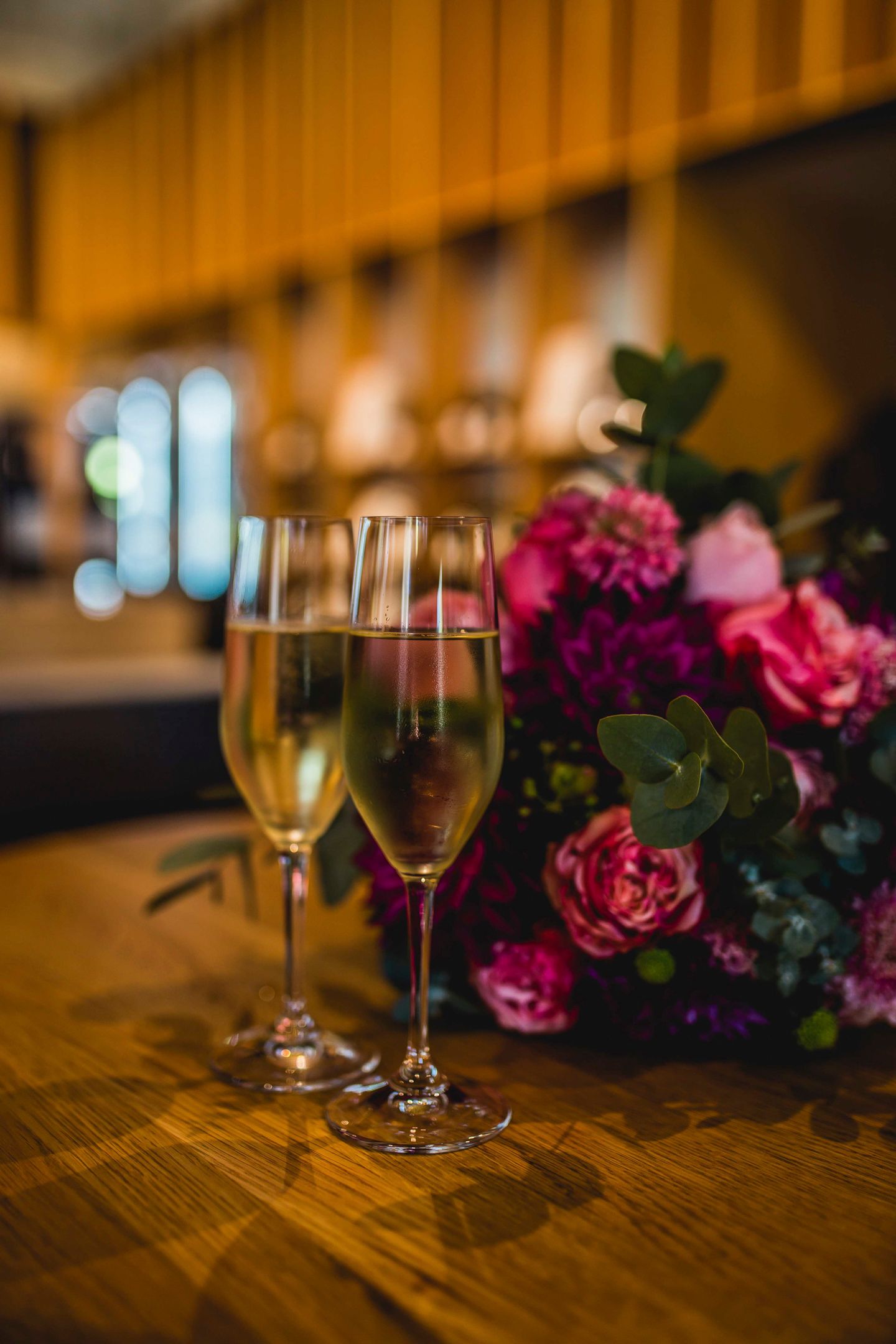 Close up detail shot of wedding champagne flutes surrounded by seasonal bridal flowers.