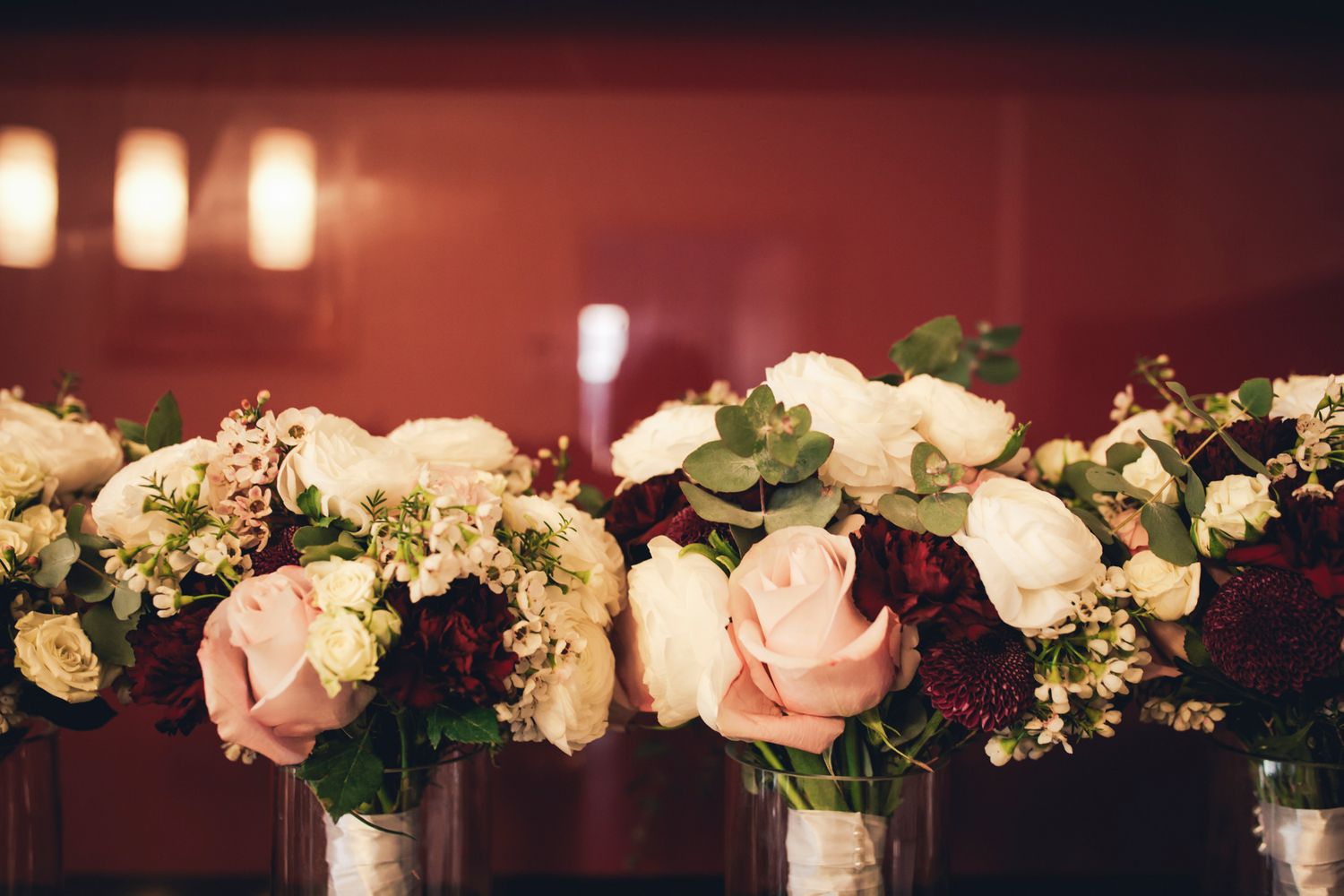 Vibrant floral arrangements by Flower Merchants against a maroon background.