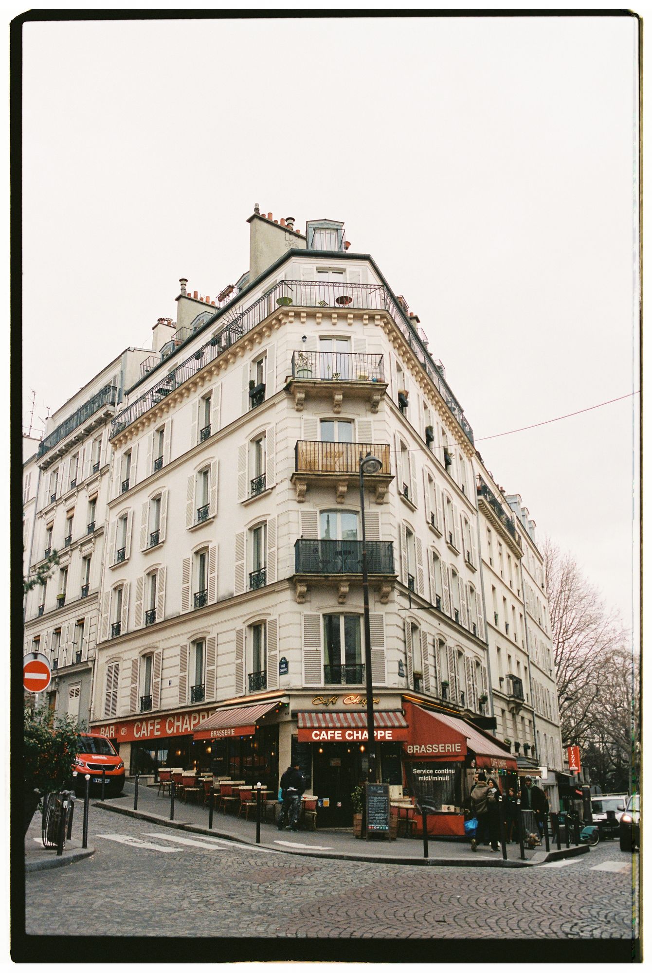 Charming Parisian street corner cafe with traditional architecture and ornate balconies in Montmartre neighborhood.