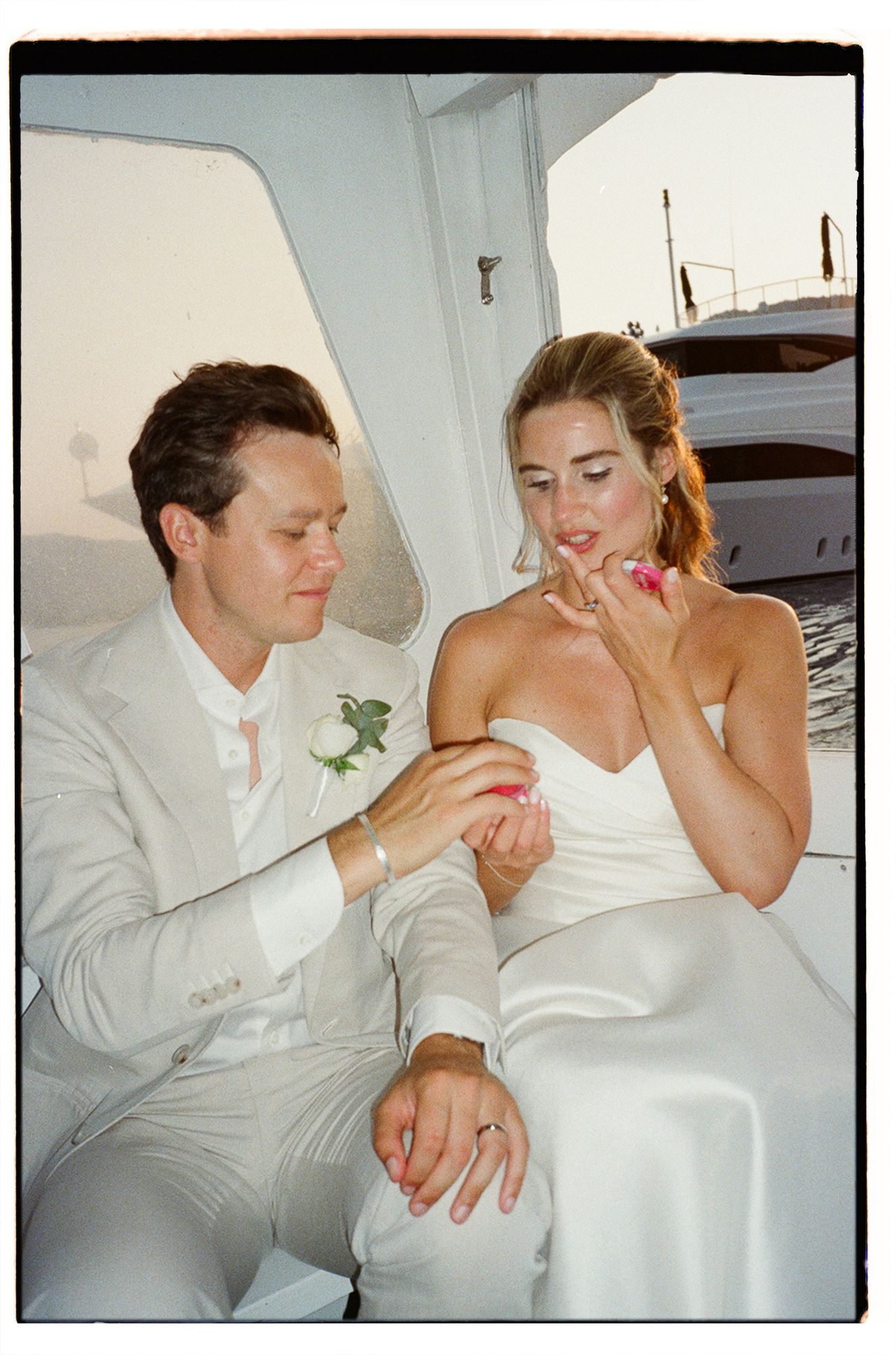 A couple in white attire share intimate moments and laughter while sitting together.