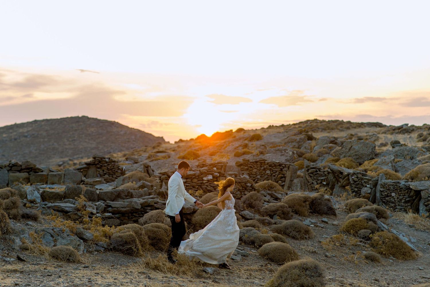 A panoramic series of desert landscape photos showing rocky terrain and dramatic sunset skies over mountains at Kythnos