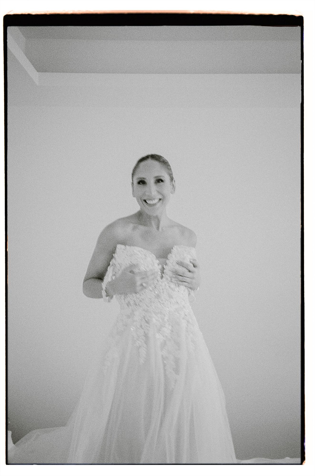 A delicate white christening gown with intricate lace details and flowing fabric shown in a black and white photograph.