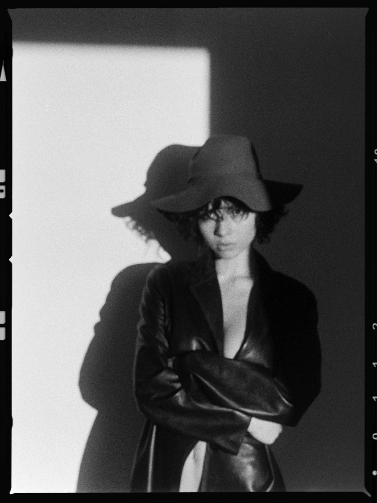 Artistic black and white portrait series showing a figure in a wide-brimmed hat casting dramatic shadows against a wall.