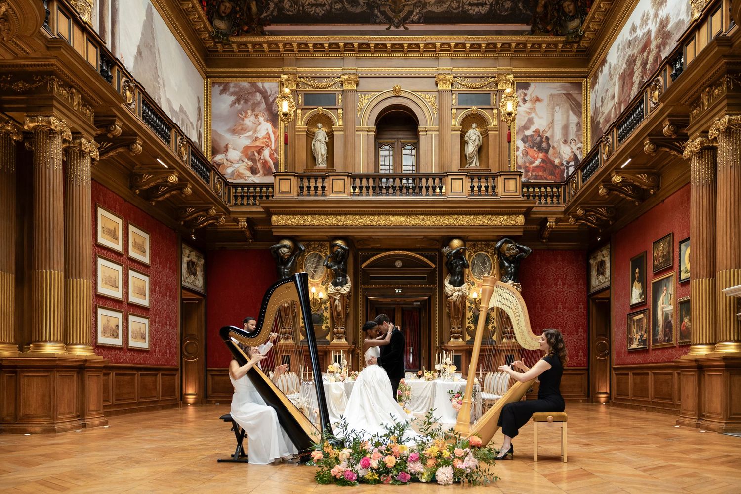 Elegant harp duet performance in ornate baroque hall with floral centerpiece and grand paintings in chateau de ferrieres wedding photograph