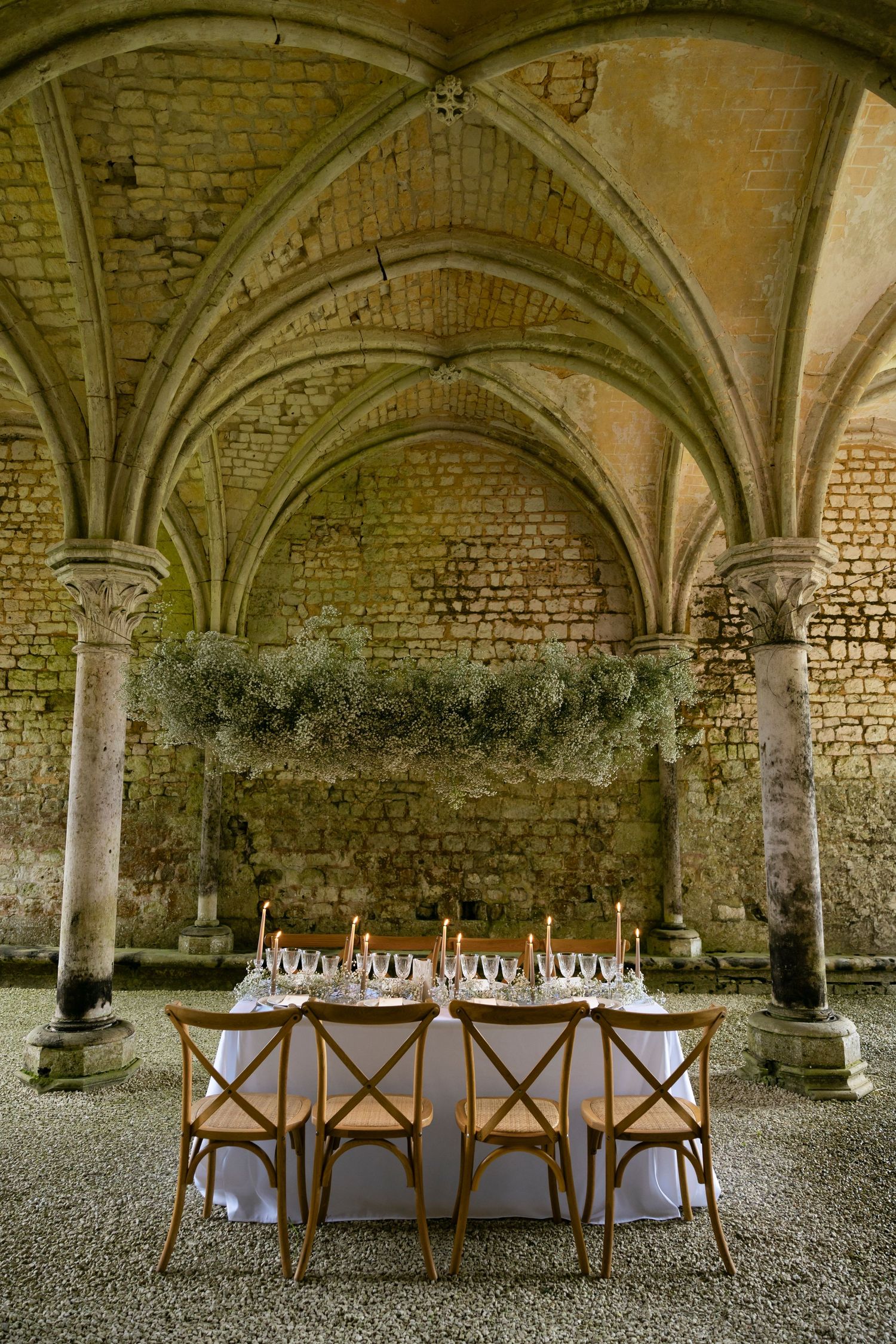 Elegant wedding reception table set under Gothic vaulted stone arches in a historic castle venue.