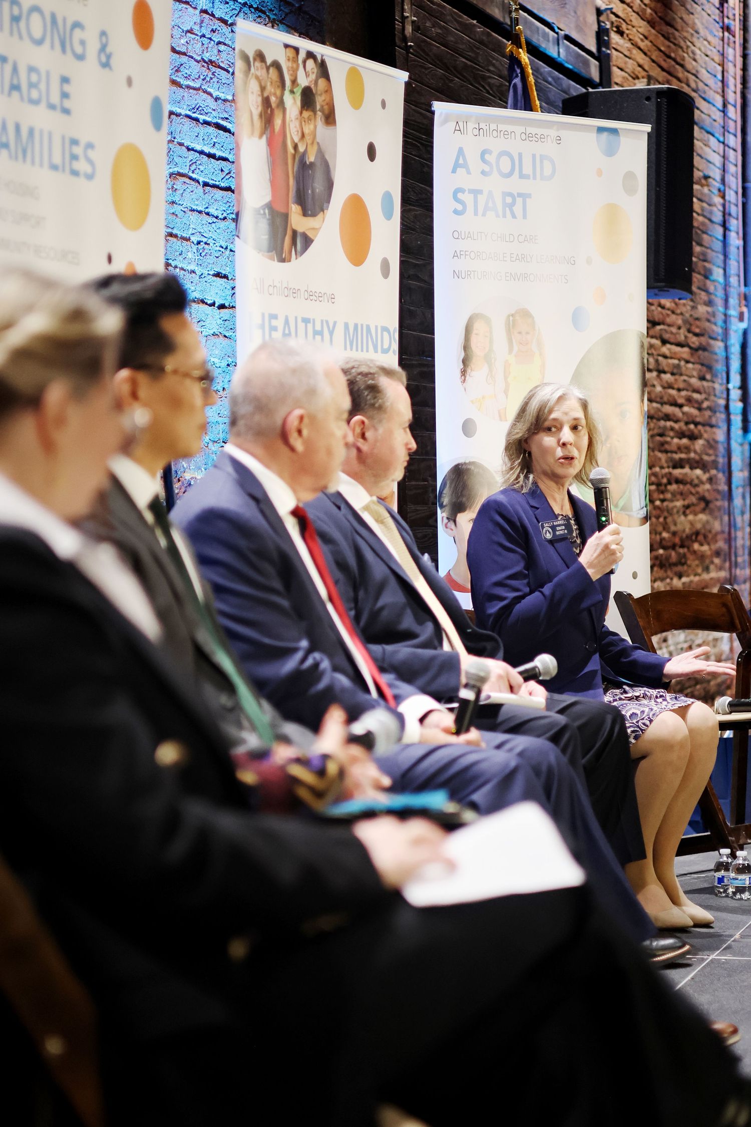 Panel discussion at a family health conference with speakers seated before banners reading A Solid Start and Healthy Minds.