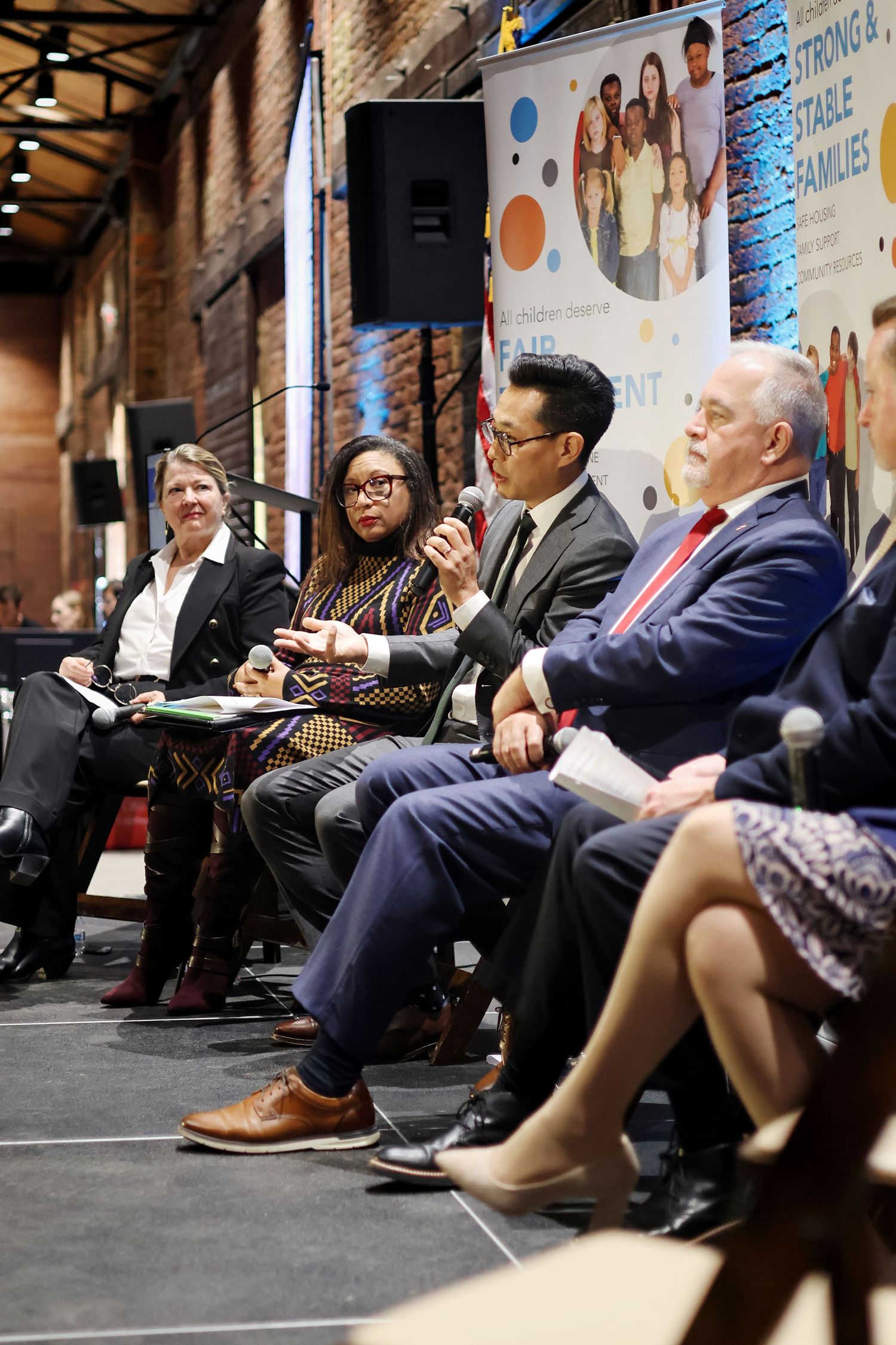 Panel of diverse professionals seated on stage at a family-focused community forum event.