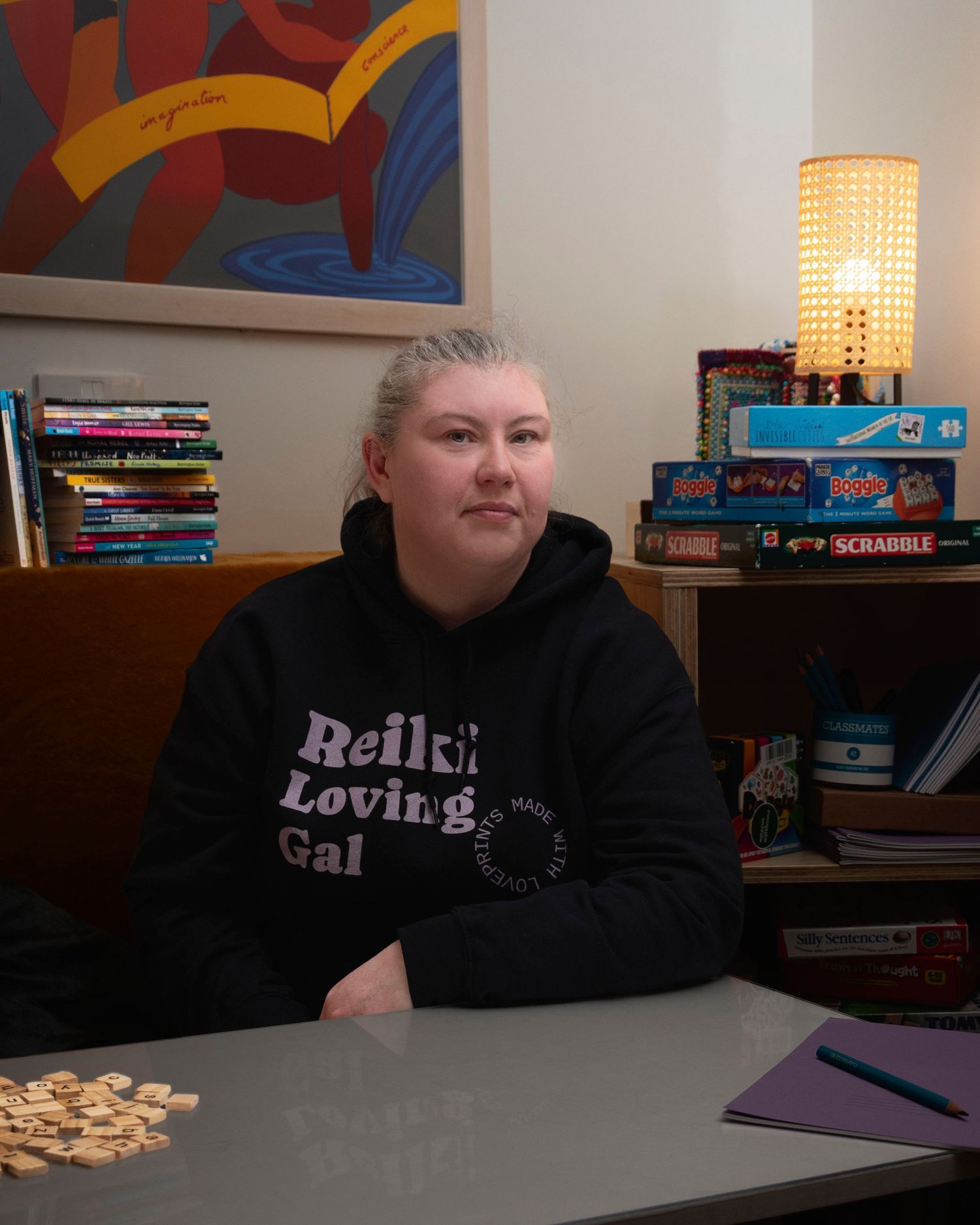 A woman seated at a table surrounded by reading books and word games