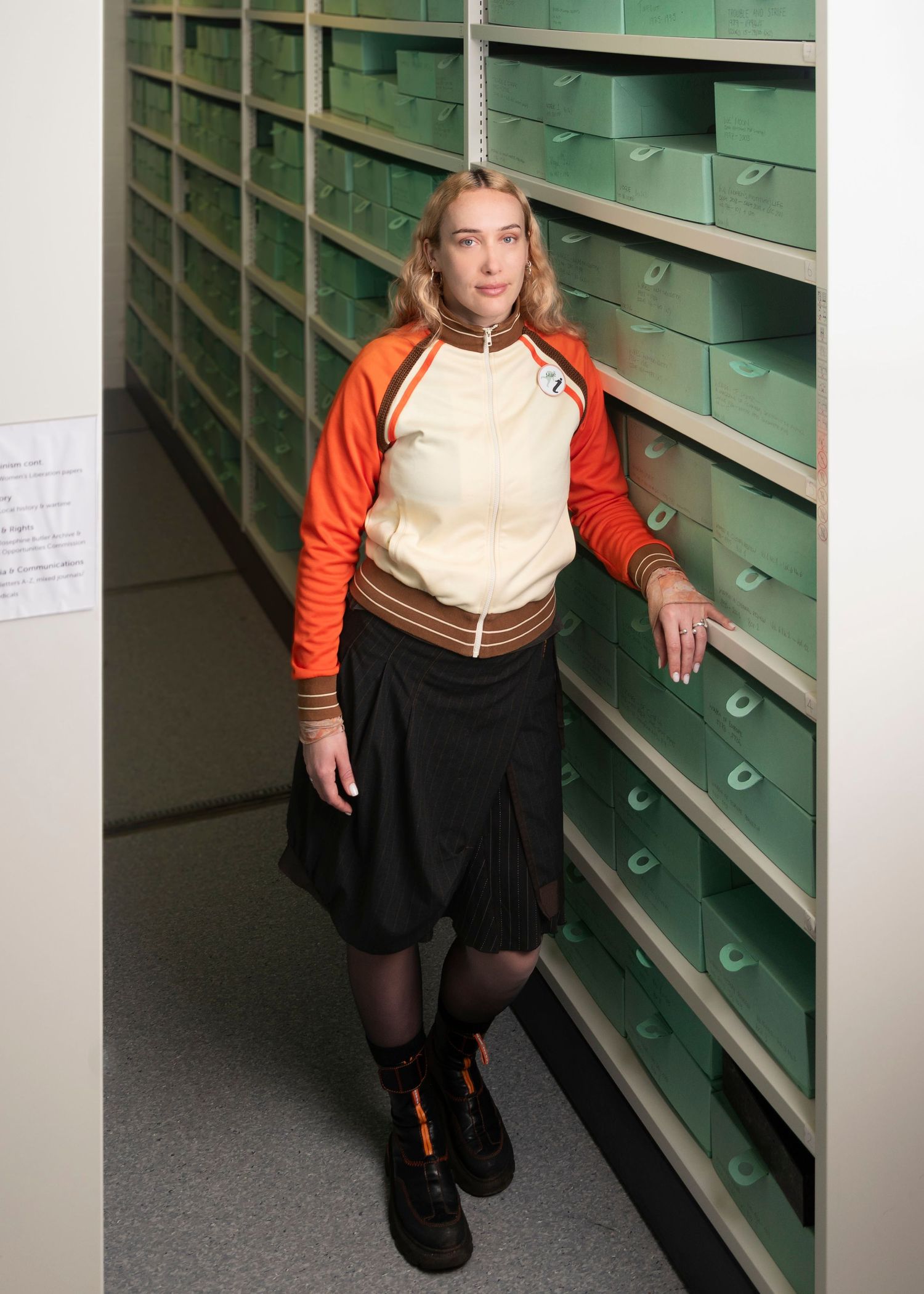 A women standing between shelves of blue archival boxes
