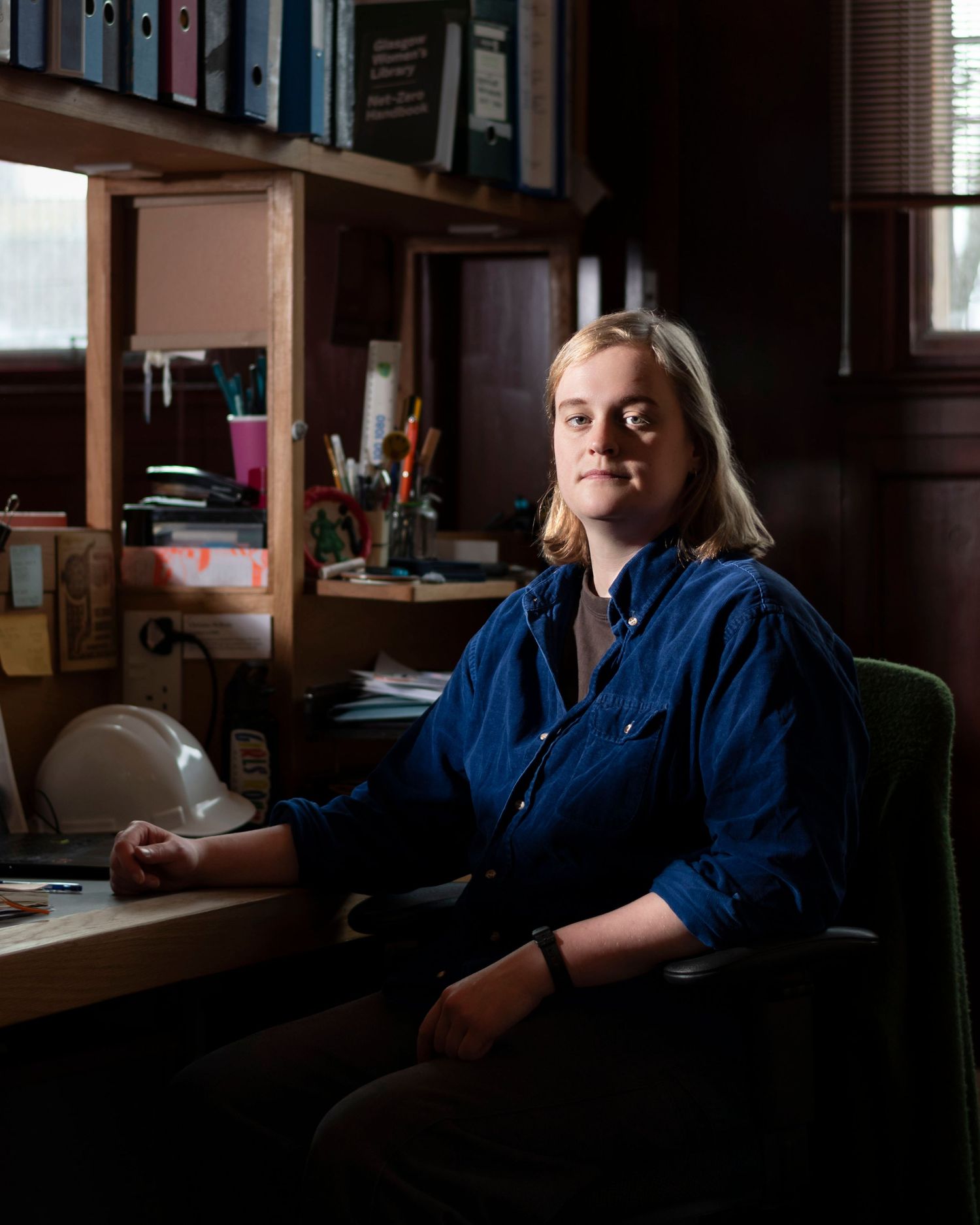 A woman seated at a desk in a cluttered office