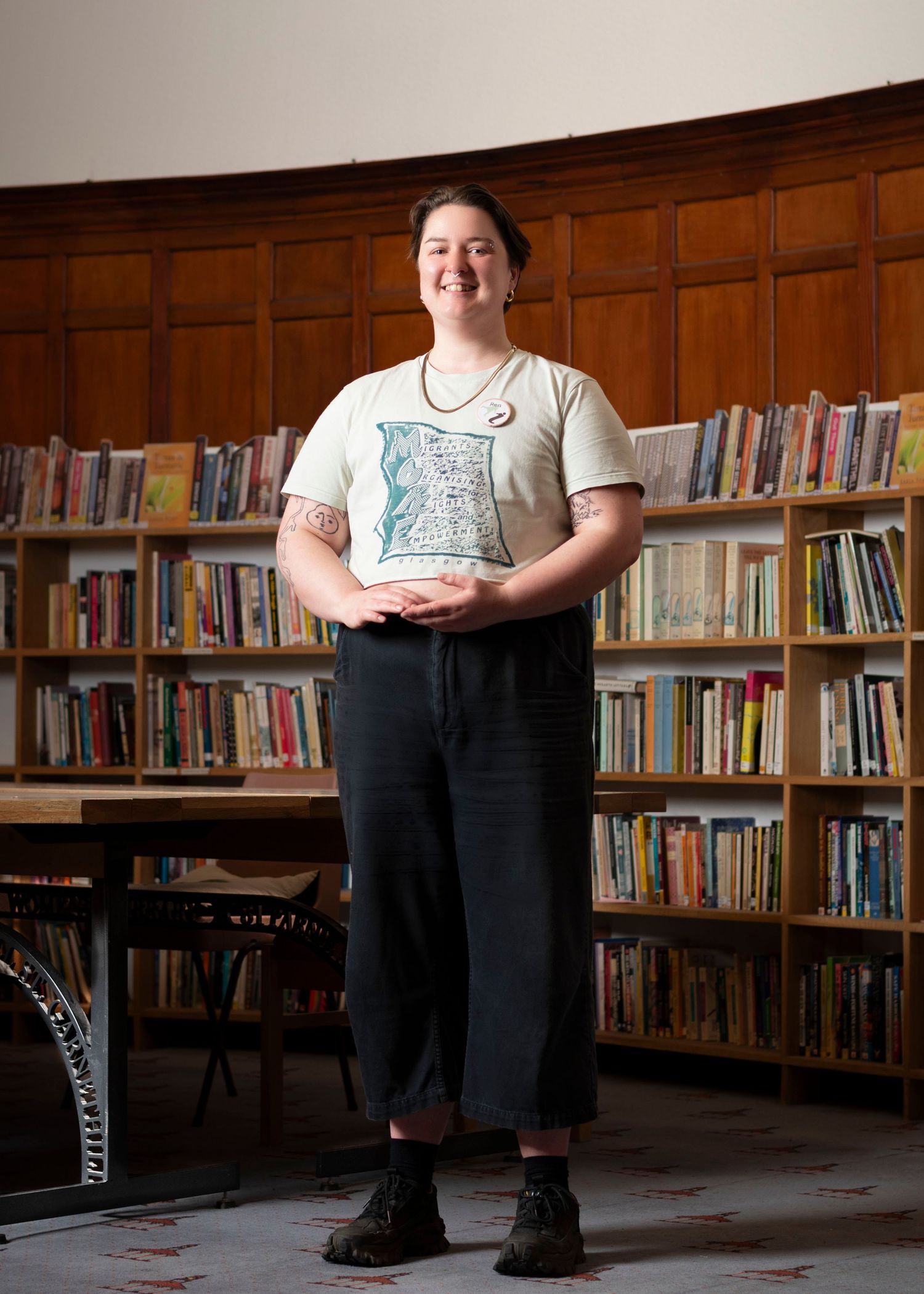 A woman standing in a library next to a large wooden table