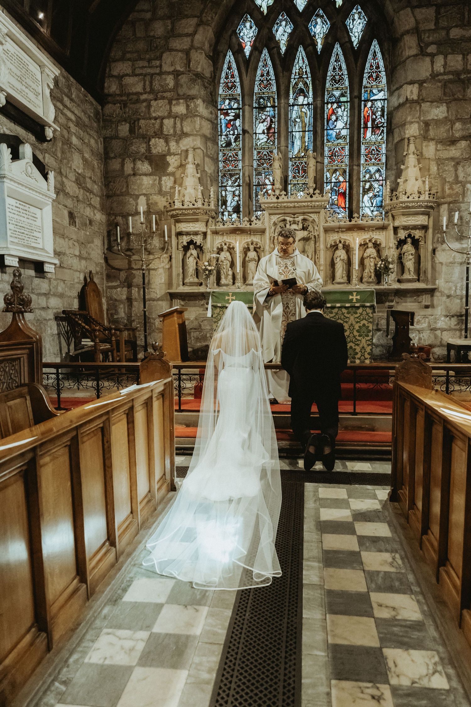 Bride and groom kneeling at top of church during catholic wedding ceremony St Wilfrids church