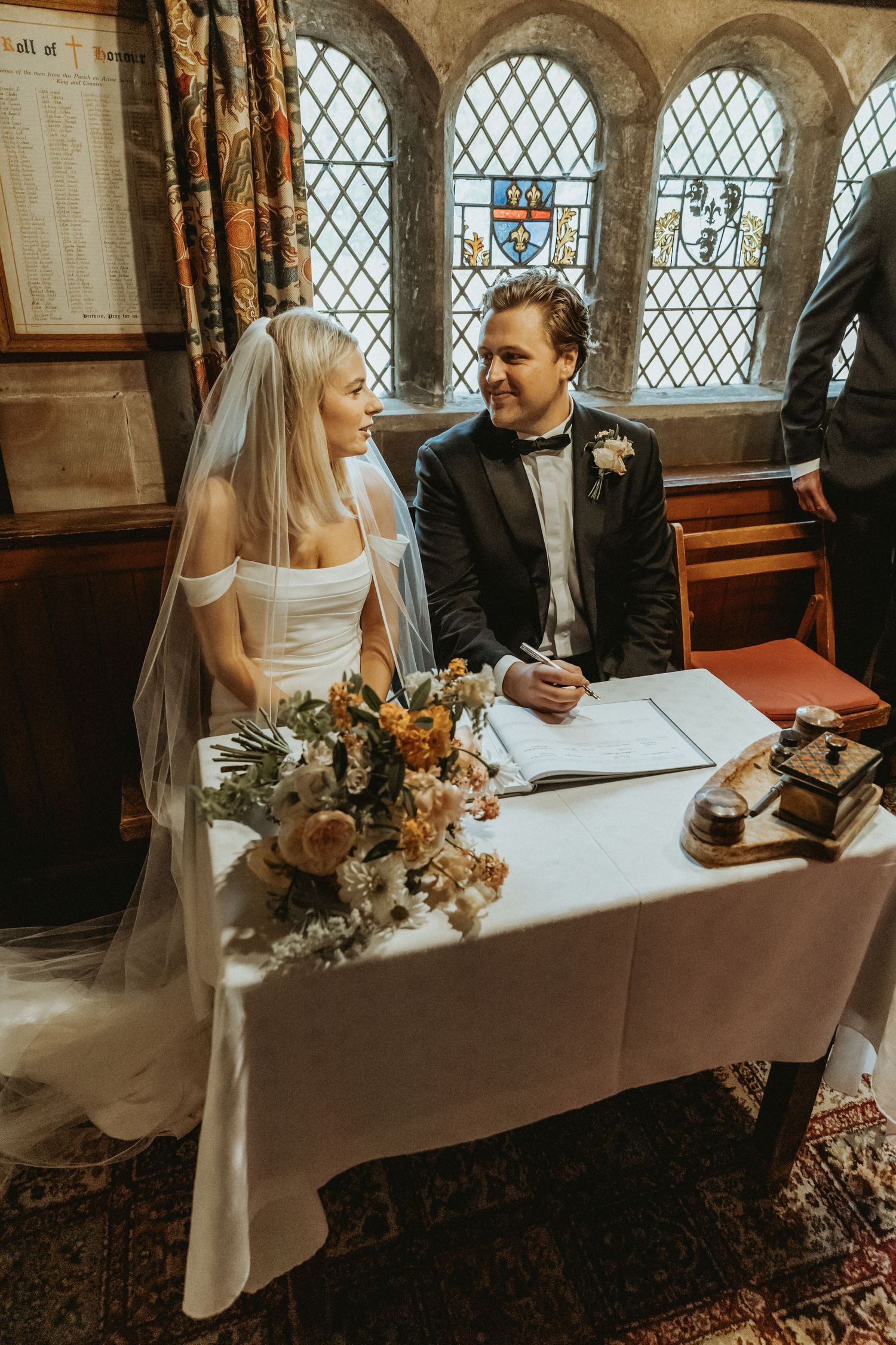 Bride and groom signing legal condiments after wedding ceremony St Wilfrids church Mobberley