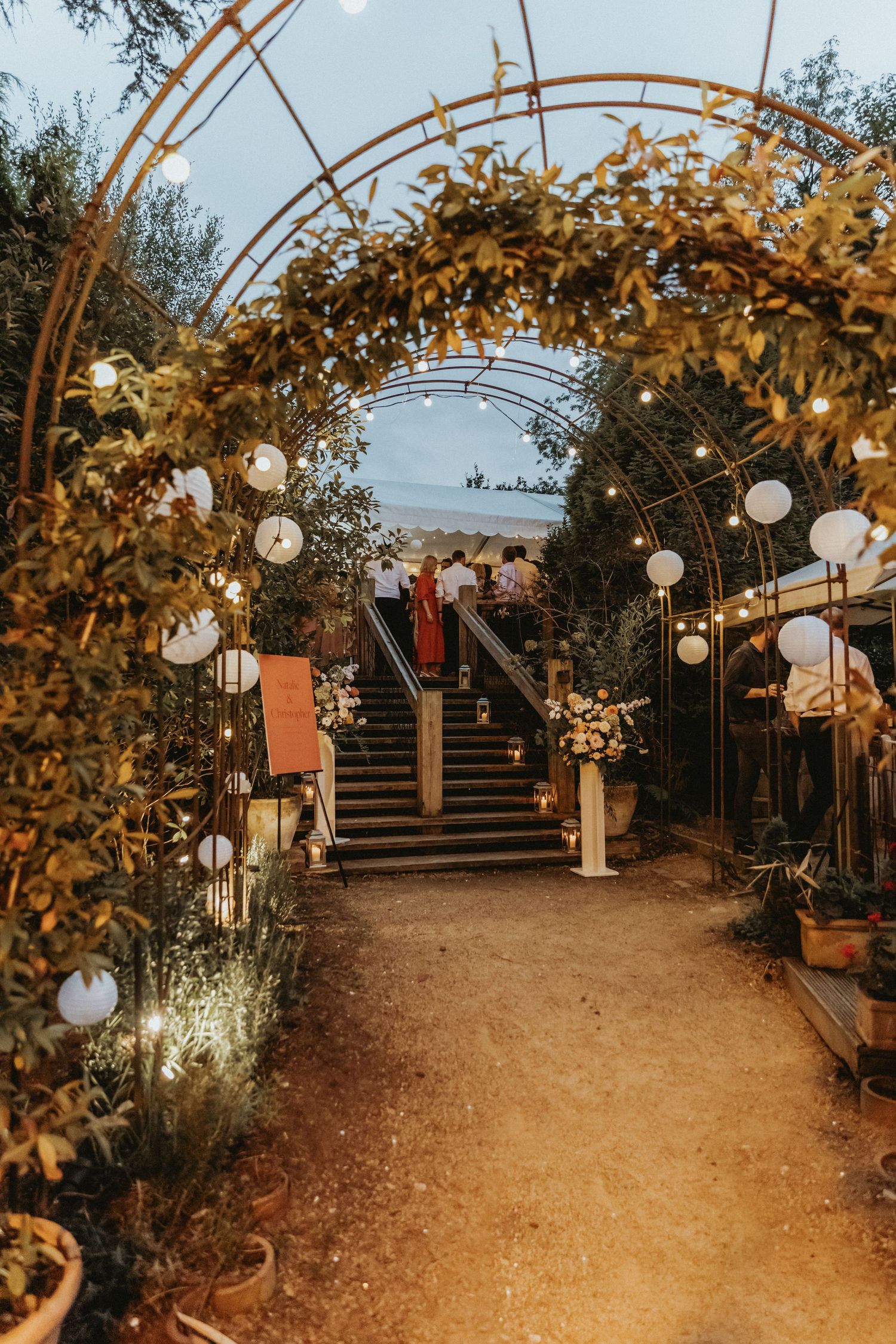 Ivy archway with lanterns leading to dance floor at wedding