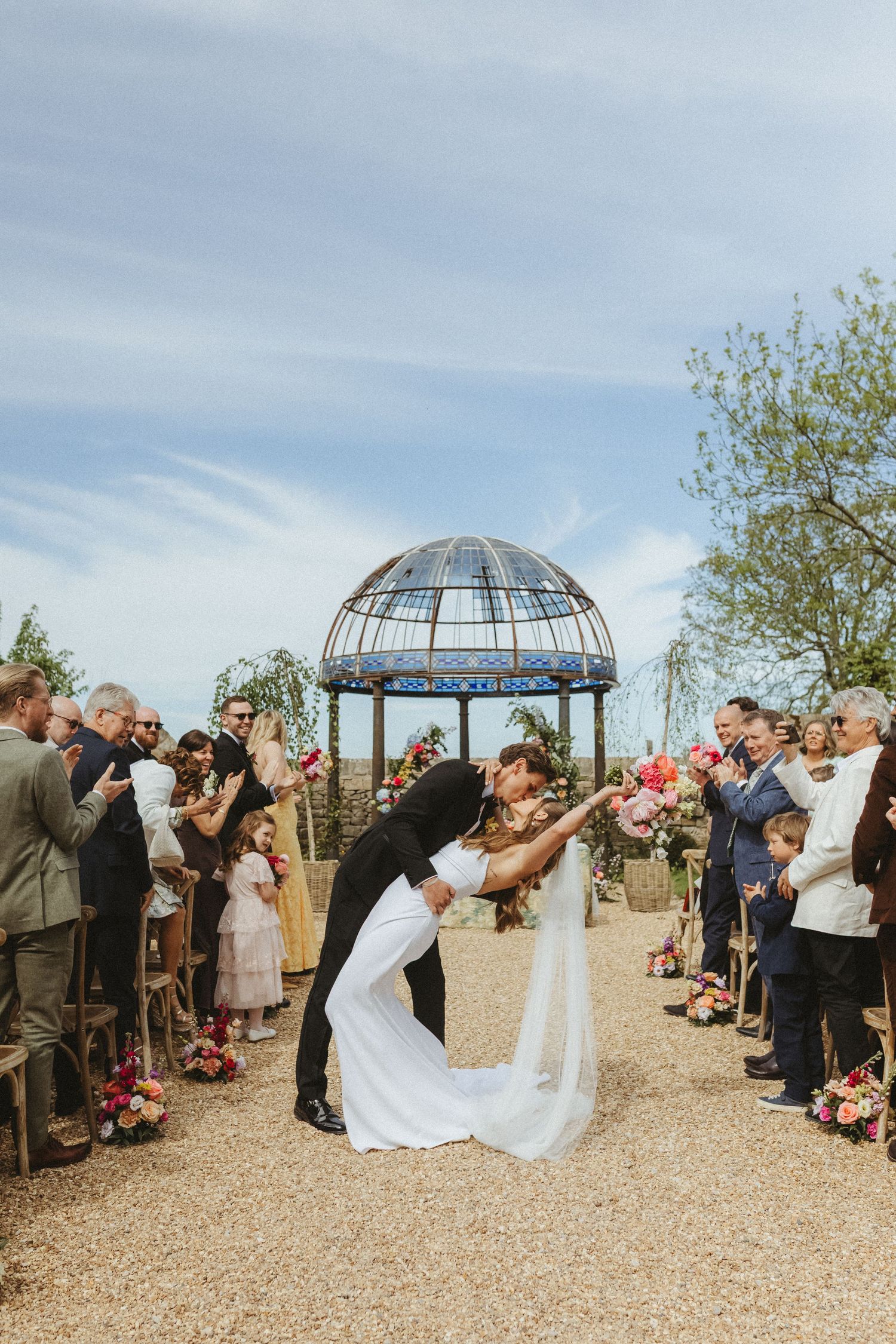 Bride and groom sharing a kiss during their aisle walk after their outdoor ceremony in Lake District