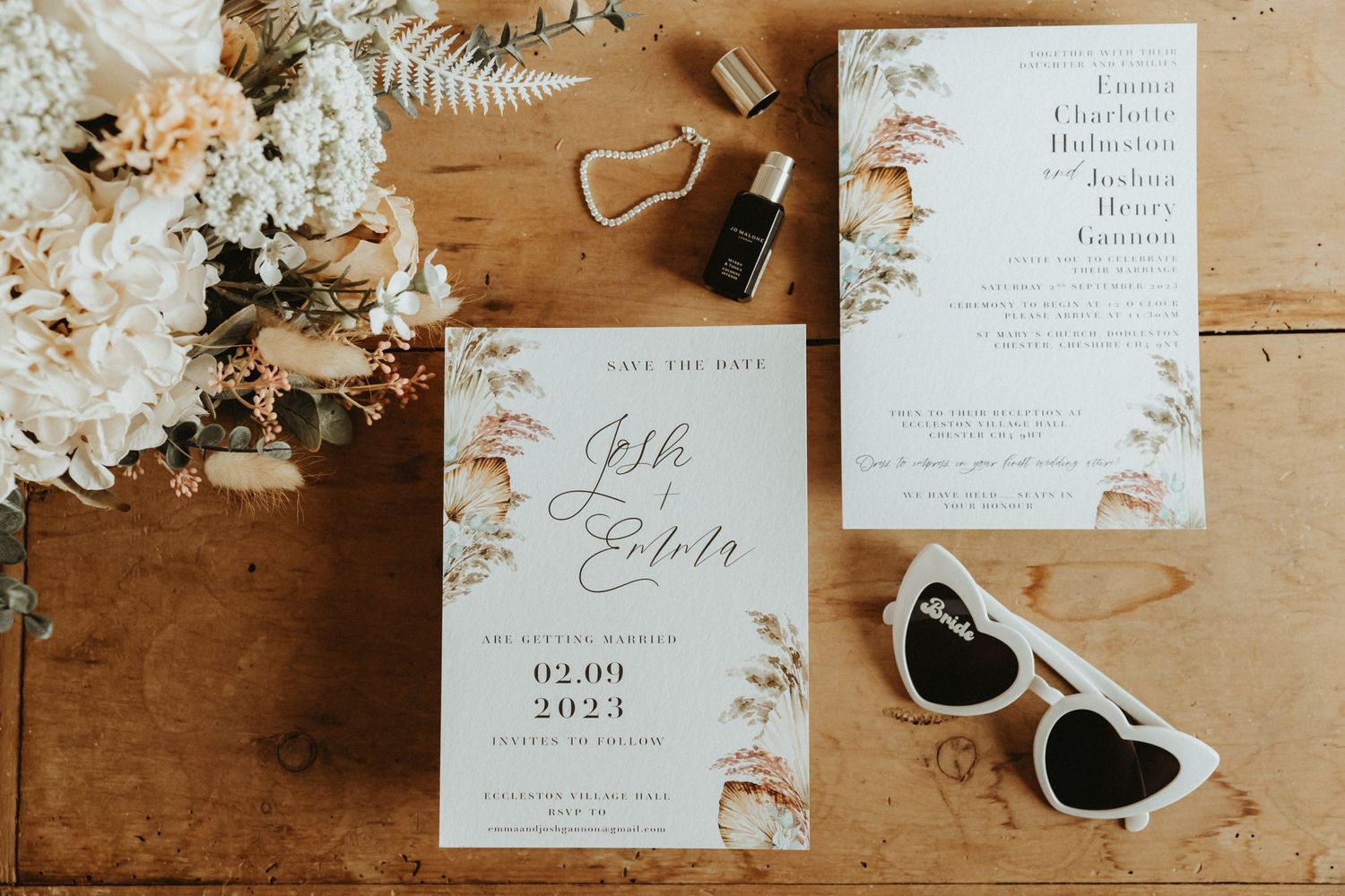 Flat lay of a wedding invitation and save the date with bridal bouquet and heart shaped sunglasses
