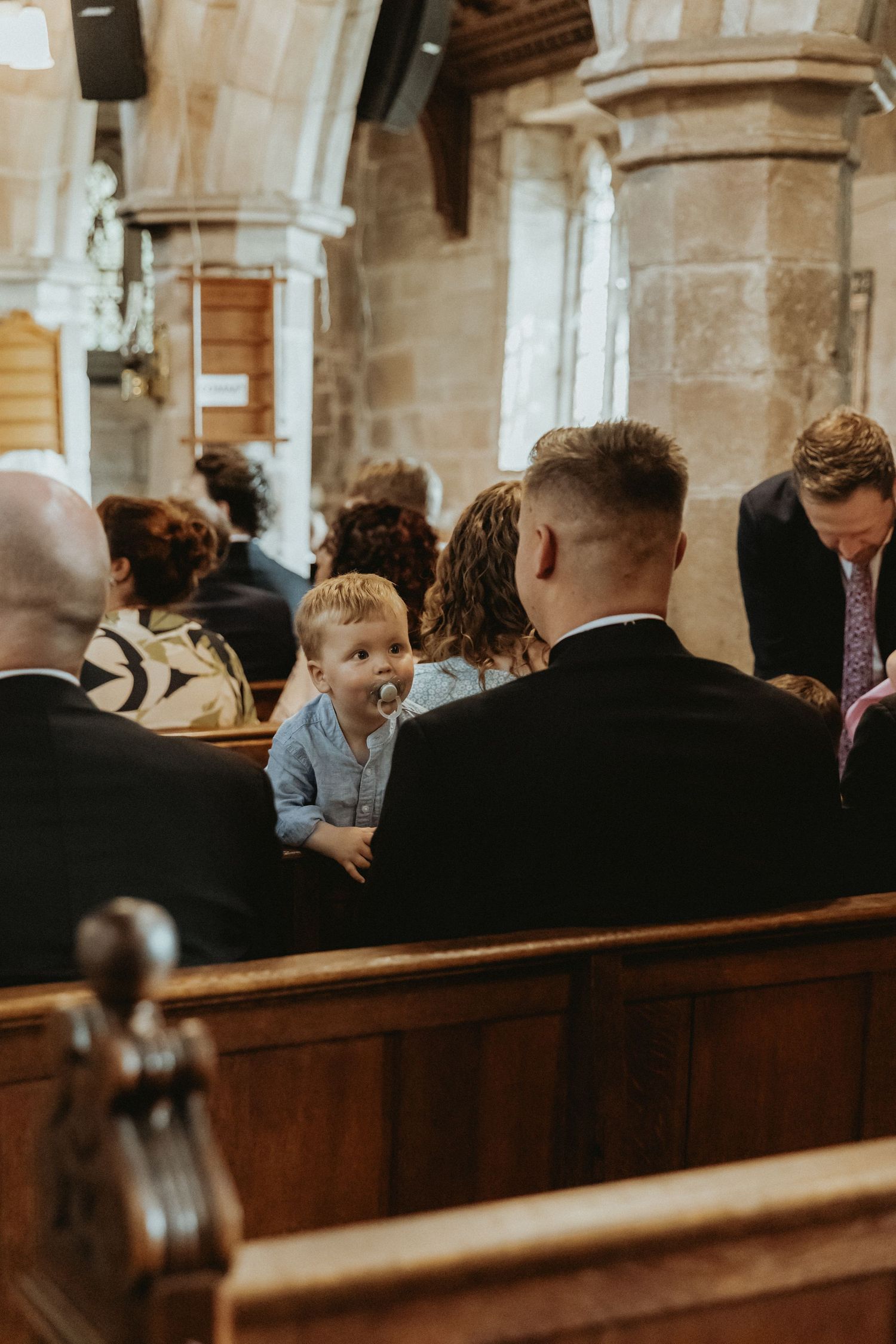 Child facing the back of the church being held during wedding ceremony St Wilfrids