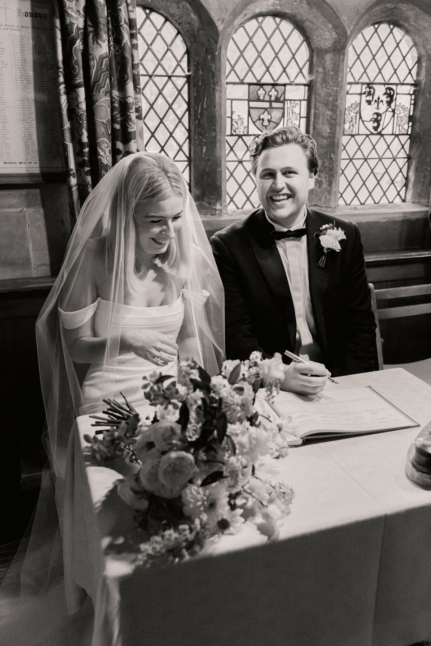 Bride and groom sharing a laugh whilst sat at a table having just signed legal documents