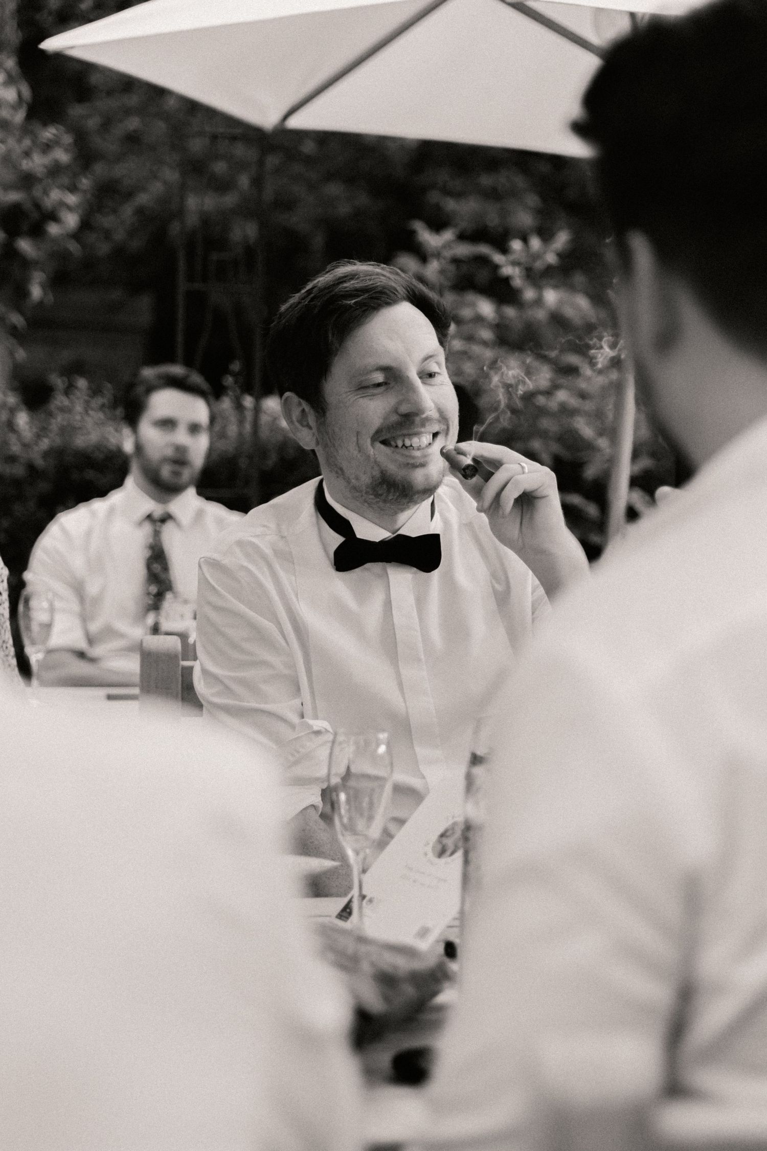 Groomsmen smoking cigar during evening of wedding outside Roebuck Inn