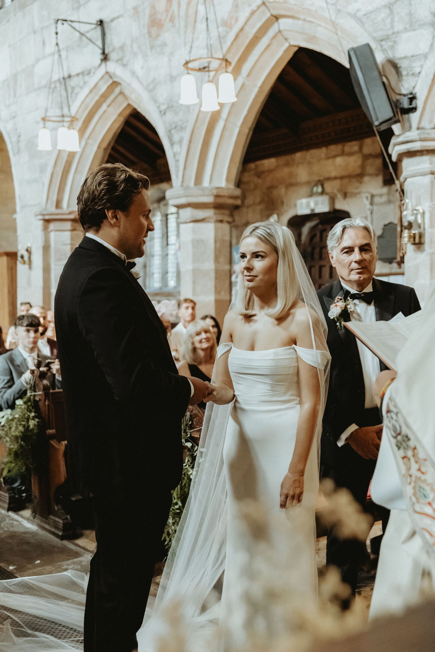 Bride and groom facing one another at top of aisle at St Wilfrids church during wedding ceremony