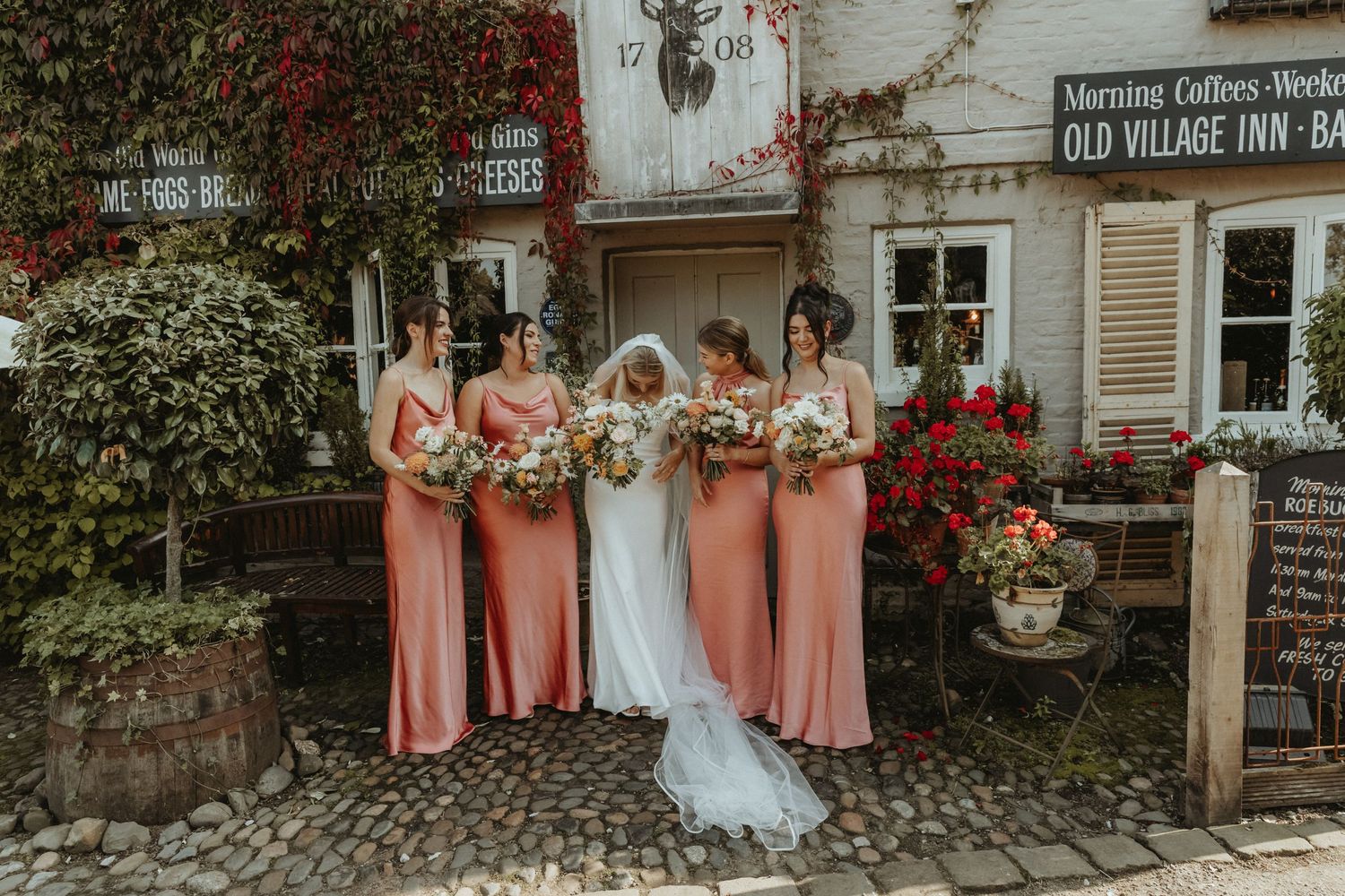 Bride standing with her bridesmaids wearing pink outside wedding venue in Cheshire