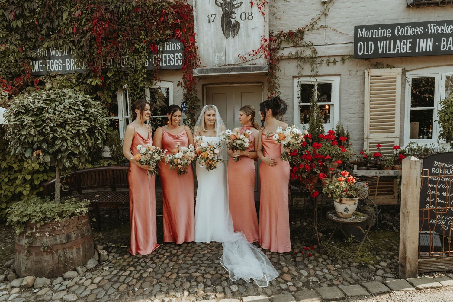 Bride standing in a line with her bridesmaids outside wedding venue in Cheshire. The Roebuck Inn