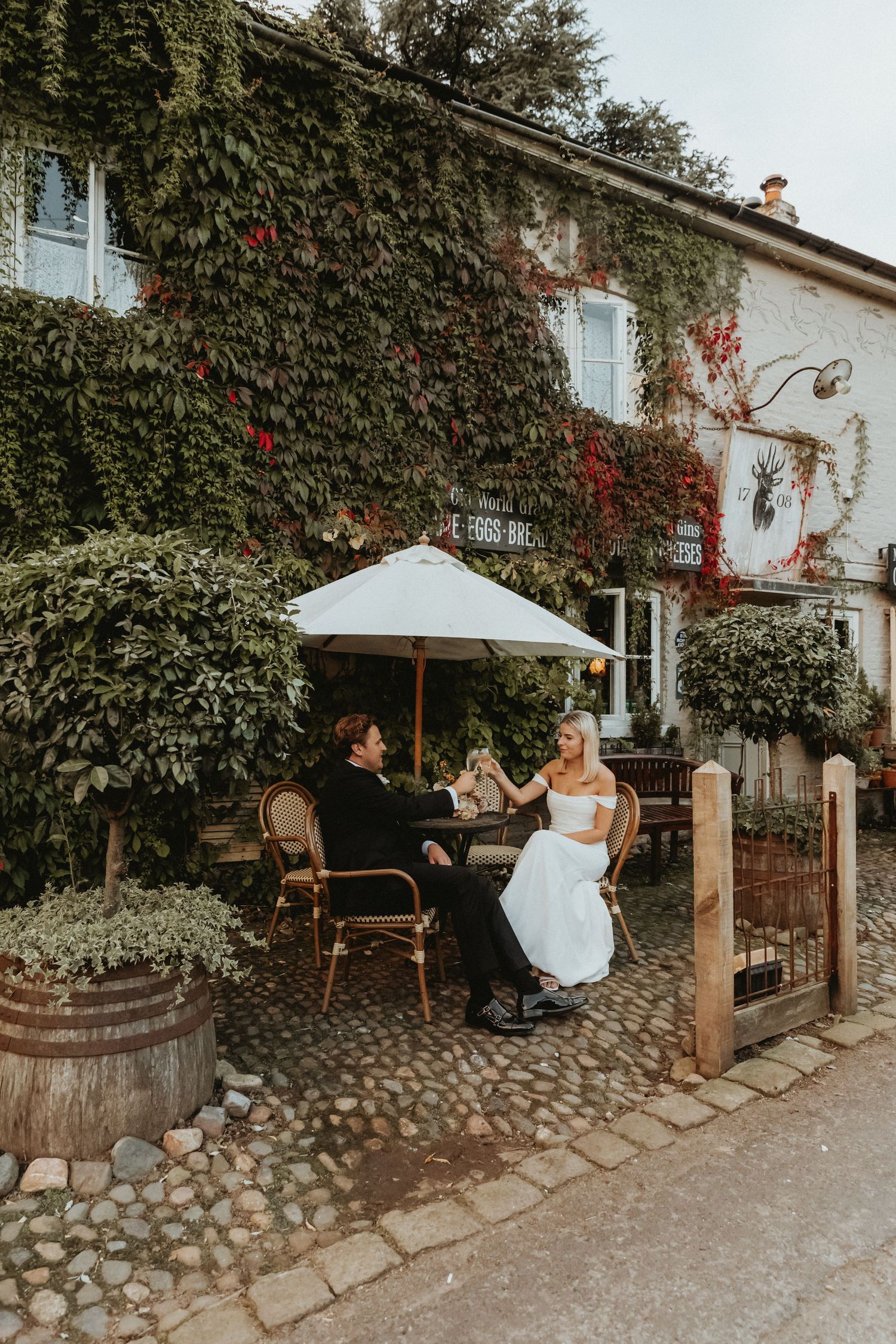 Bride and groom sat toasting outside The Roebuck Inn in Cheshire on their wedding day