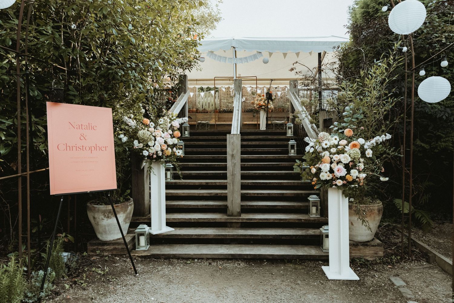 Flowers on stand at the bottom of steps leading up to dance area at wedding evening