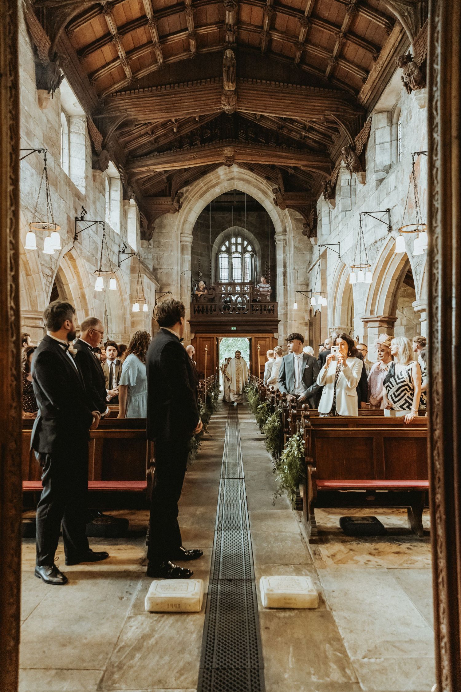 Groom facing the back of the church watching as bride enters St Wilfrids church in Mobberley