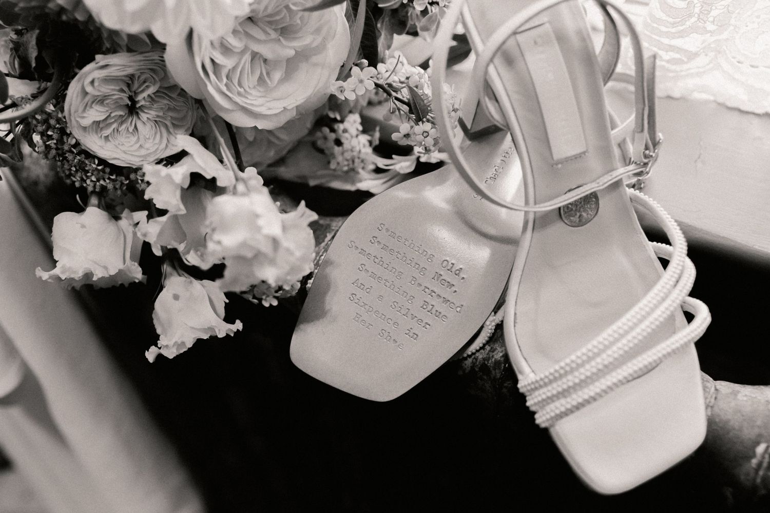 Black and white photo from bridal prep of bouquet and brides shoes on window sill at Roebuck Inn