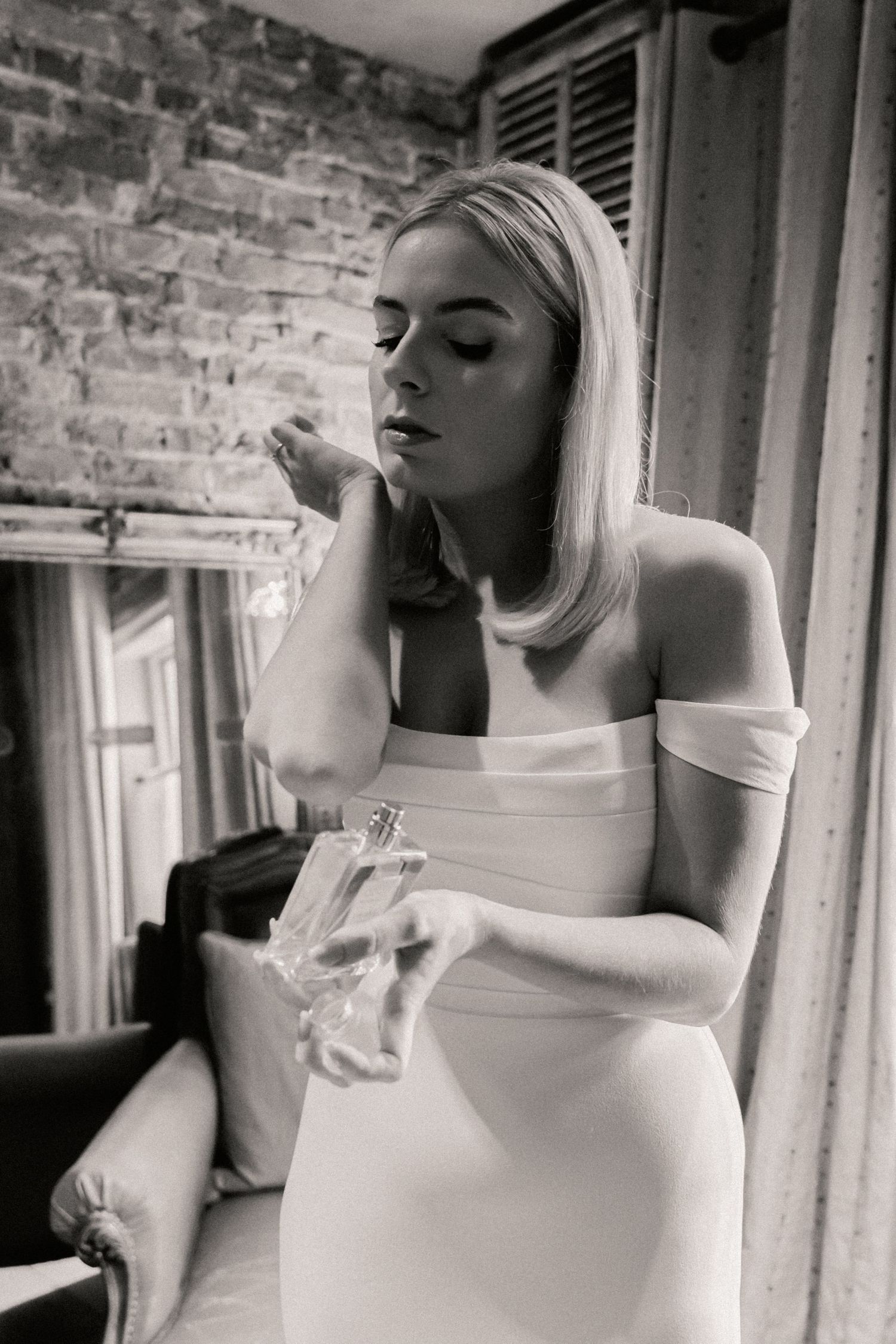 Bride applying fragrance onto neck with wrist in black and white