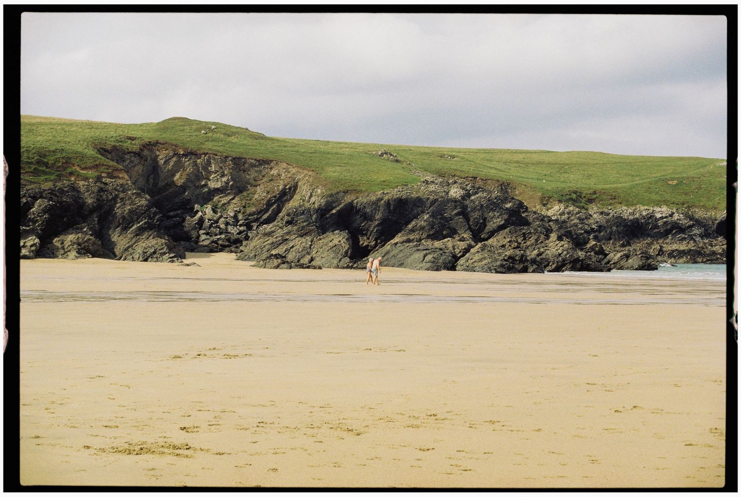 Couple walking along beach in Cornwall on summers day taken by a wedding and elopement photographer
