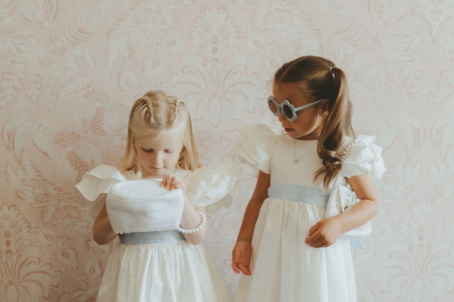 Flower girls looking inside their new white handbags before wedding ceremony at Askham Hall