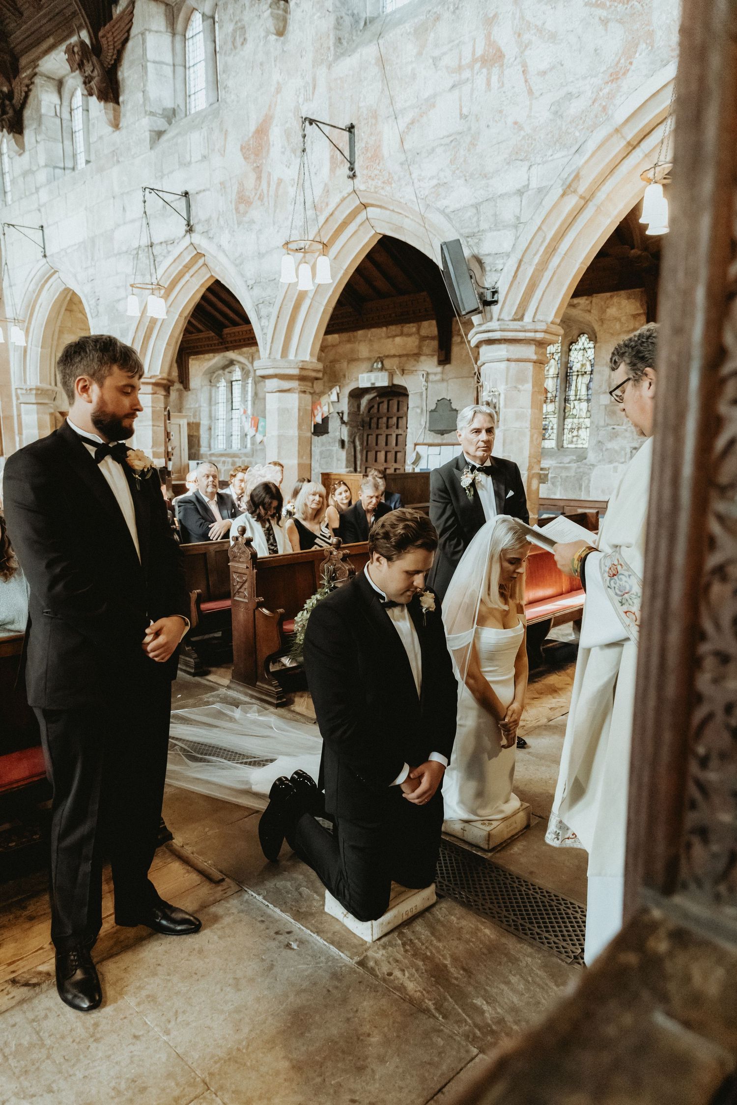 Bride and groom kneeling at top of church during catholic wedding ceremony St Wilfrids church